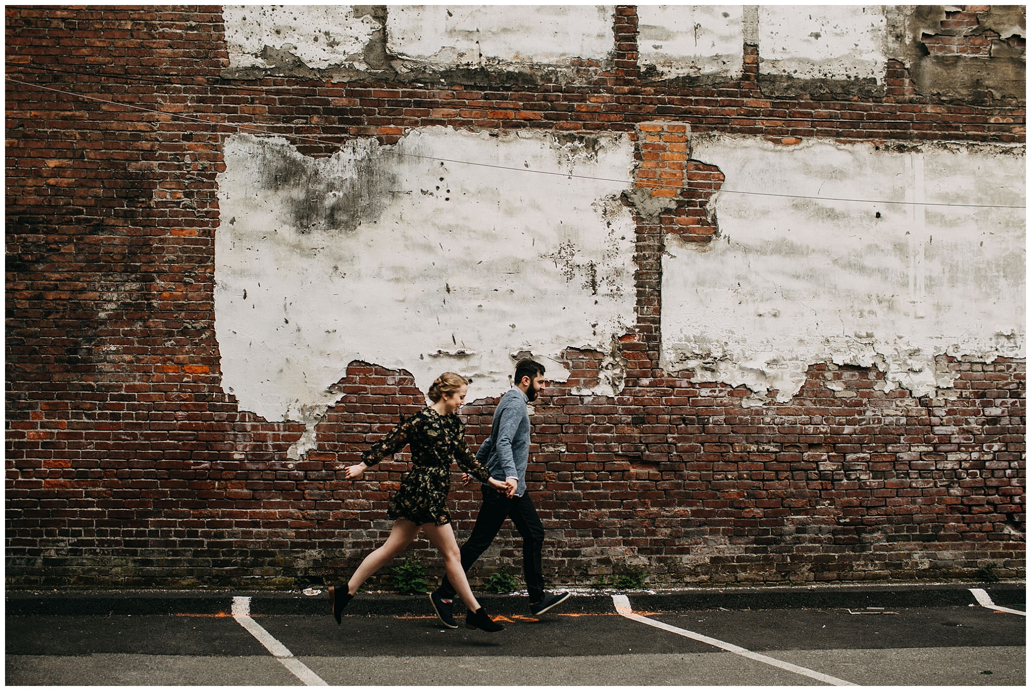 couple dancing in front of brick wall at downtown new west engagement session