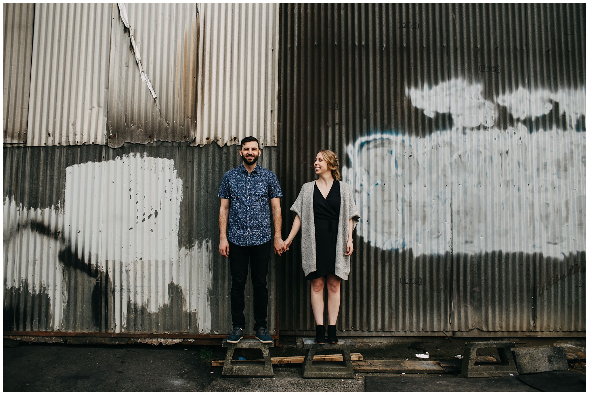 couple holding hands in industrial urban setting at downtown new west engagement session