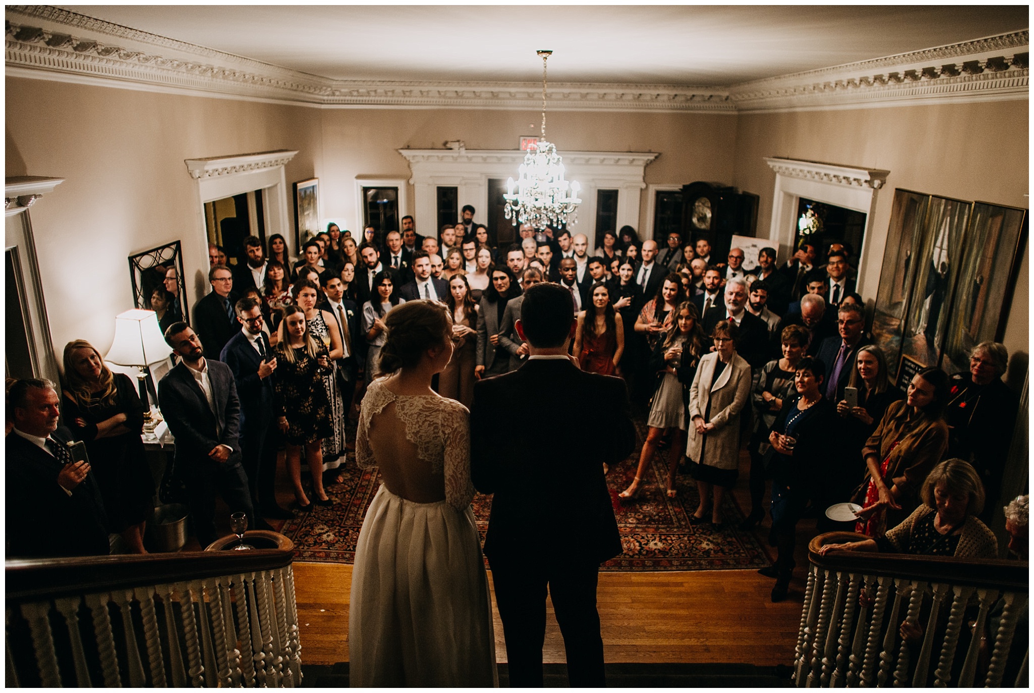 bride and groom speeches with guests surrounding at grand staircase