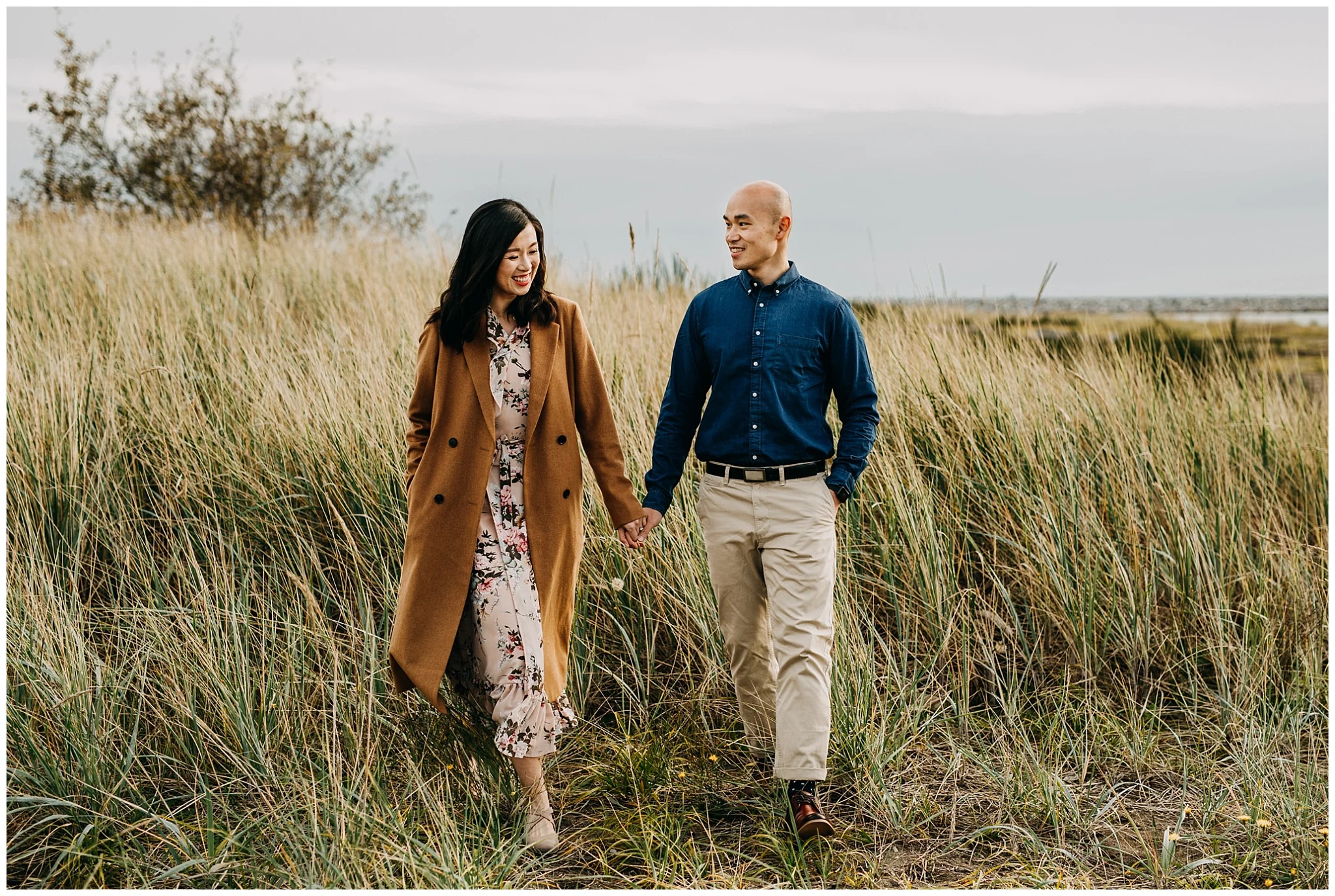 couple walking in tall grass at iona beach engagement session