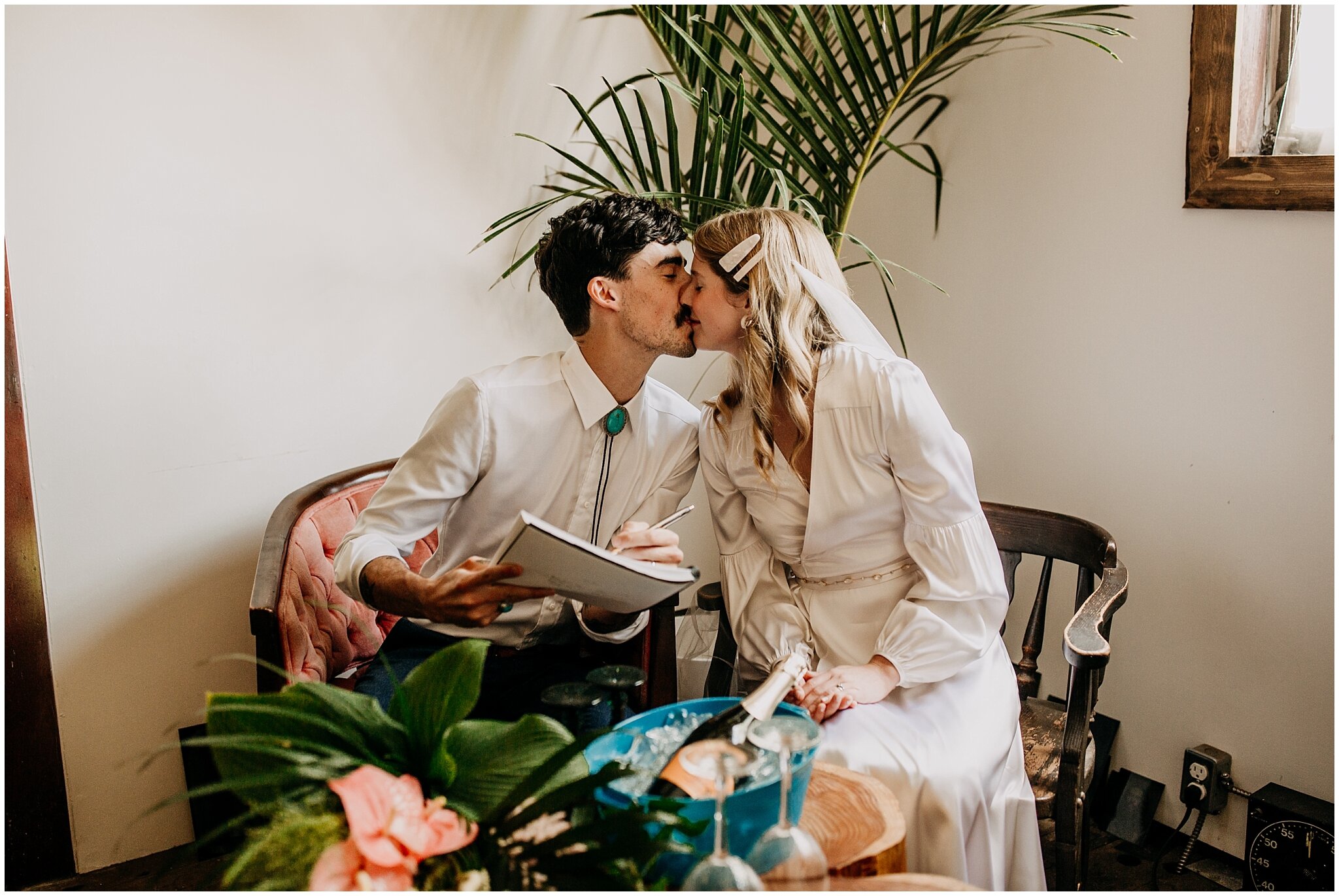 bride and groom signing papers at ellis building wedding