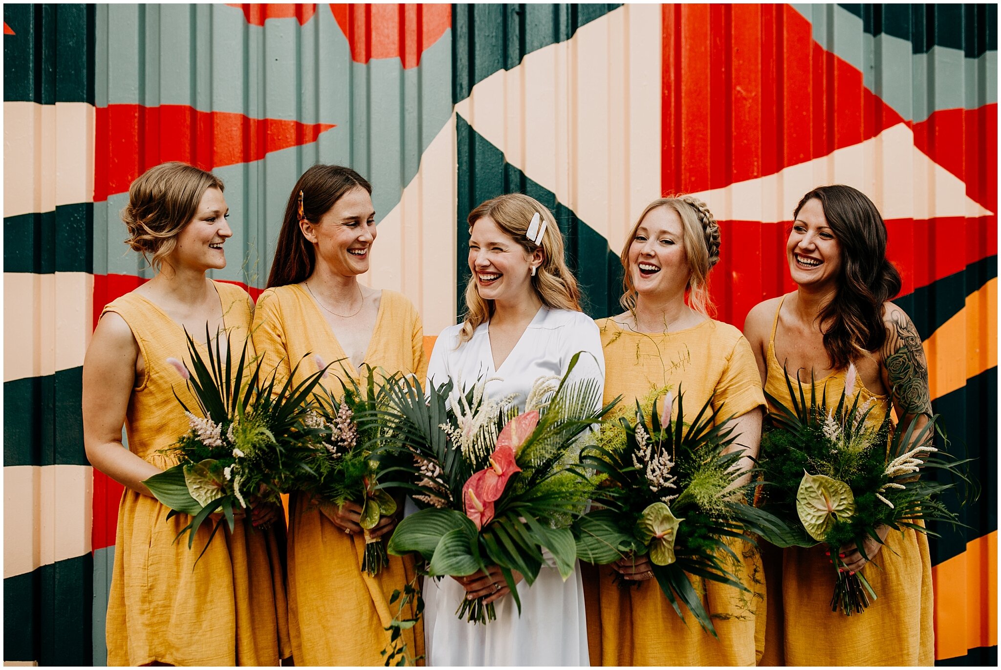bride and bridesmaids portrait in front of mural at ellis building wedding