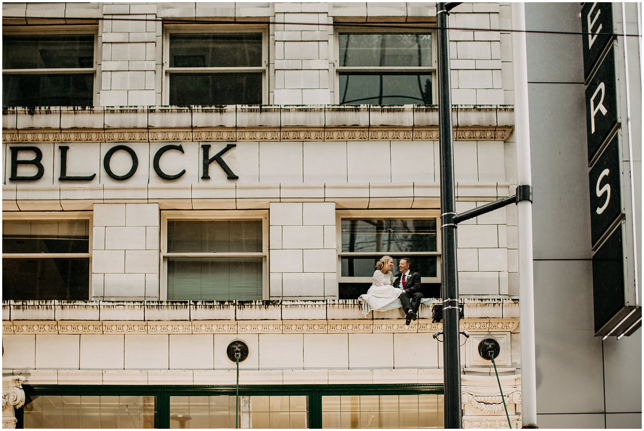 bride and groom sitting outside window in vancouver block building