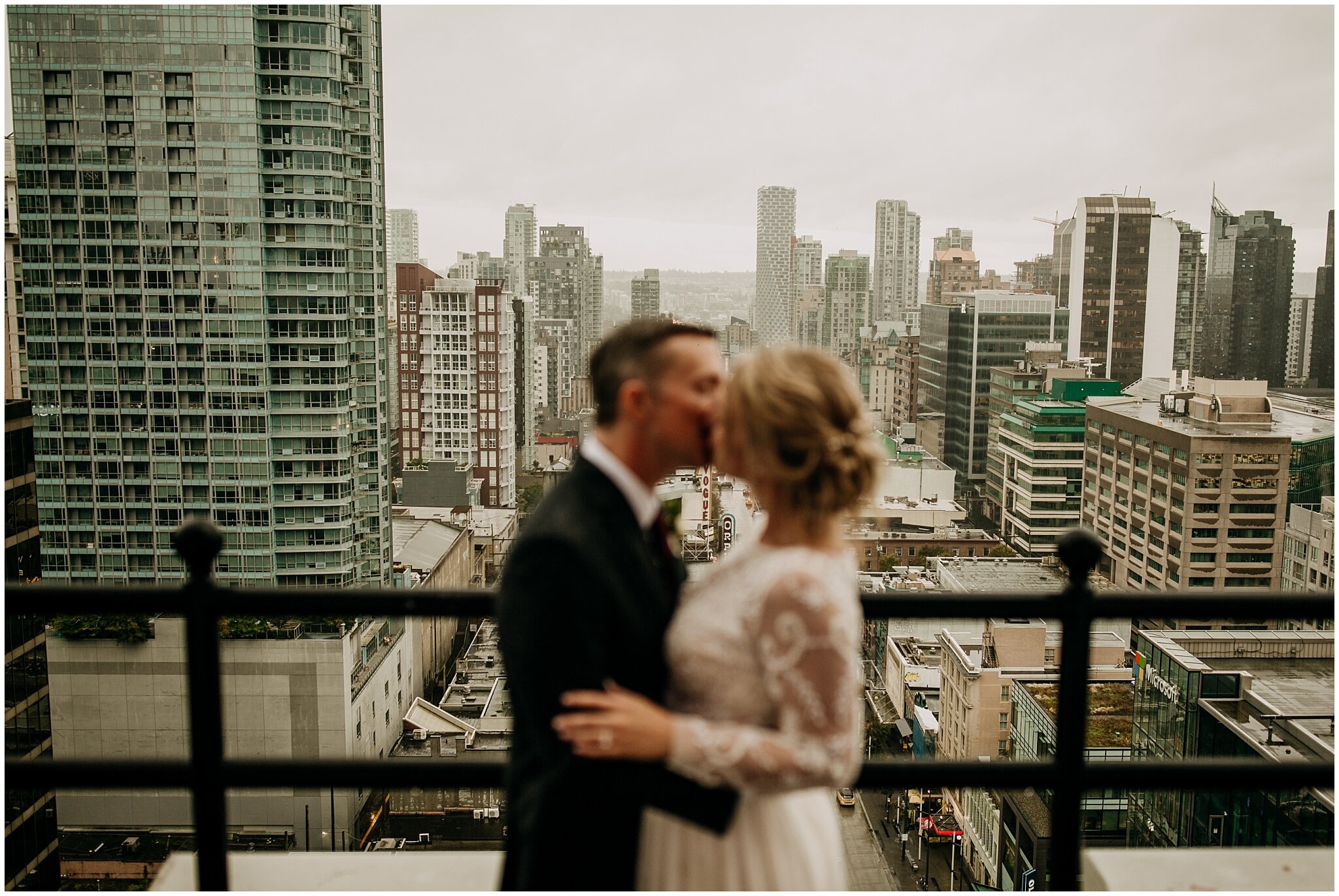 bride and groom in front of city view on vancouver block building rooftop