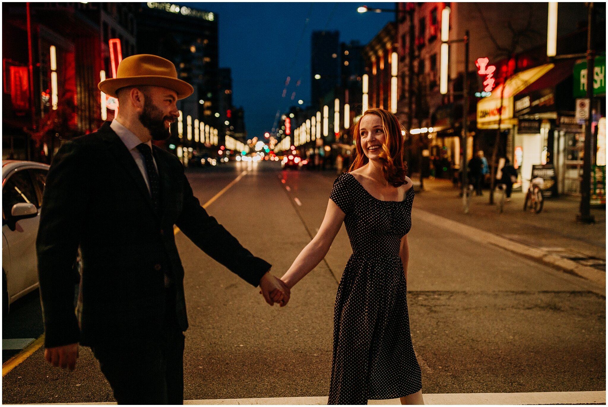 couple walking down granville strip at night for engagement photos