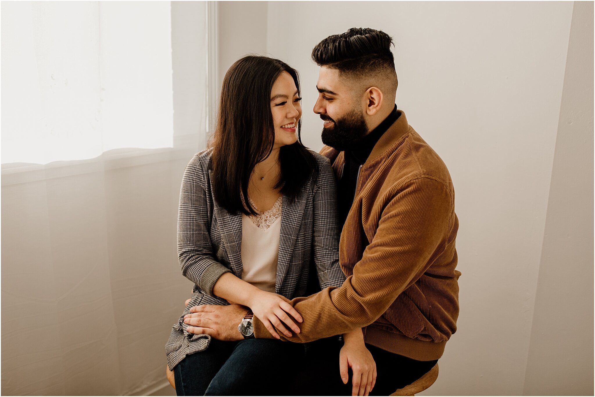 vancouver natural light studio couples portrait of couple sitting on stools and smiling