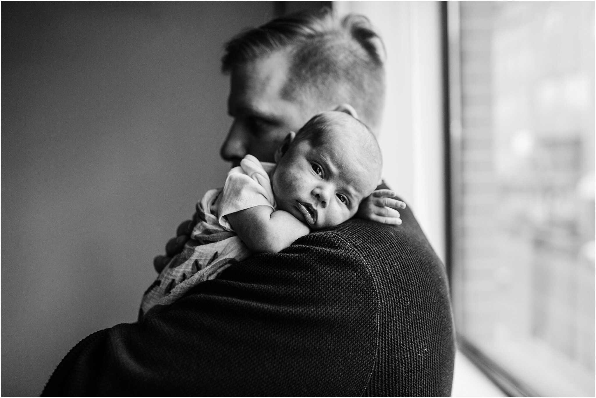 black and white studio portrait of dad holding his baby in vancouver