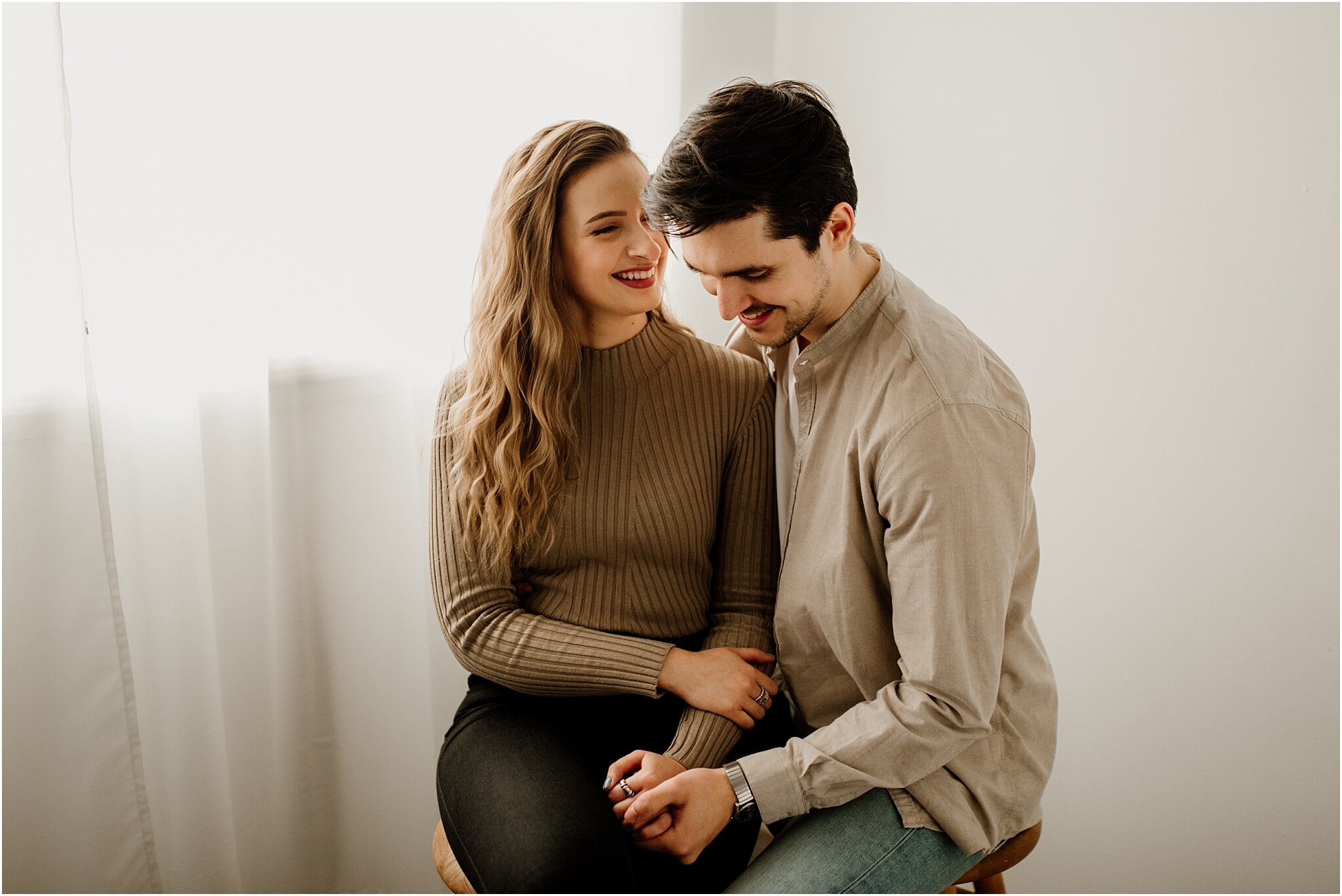 natural light portrait of couple sitting on stools in front of window