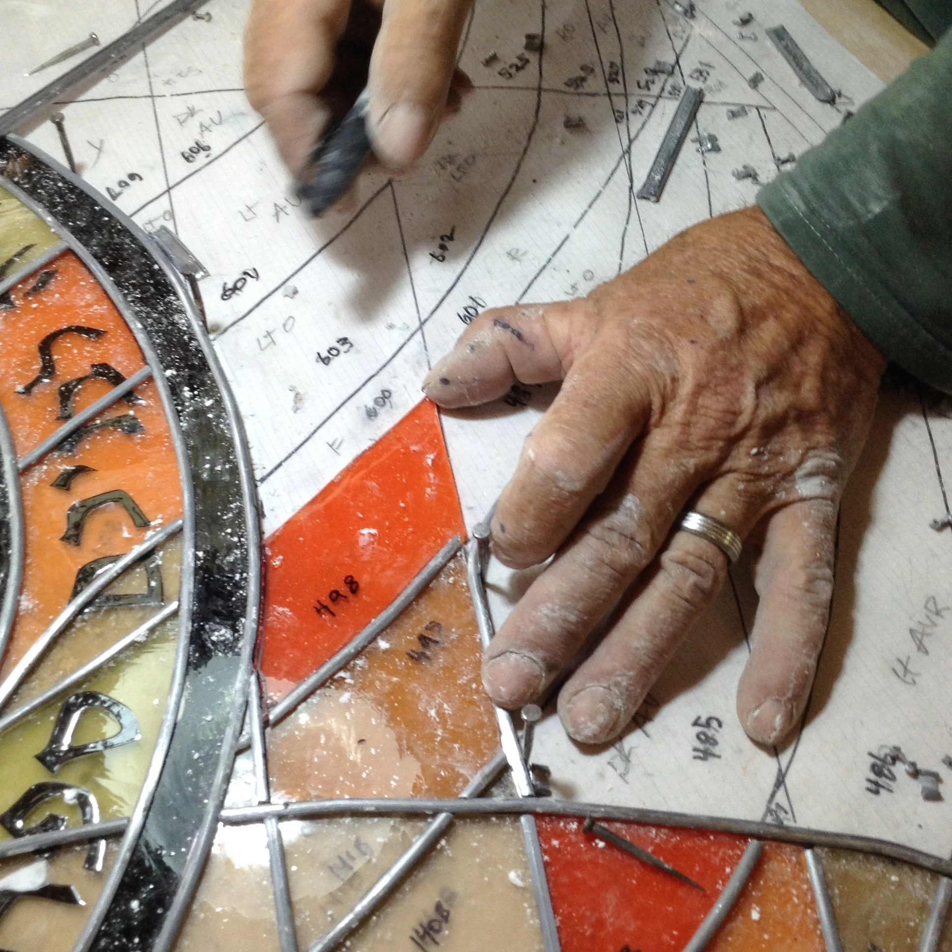 After grinding, the glass piece is checked again for fit and inserted into the channel, fitting precisely inside the lines on the pattern.