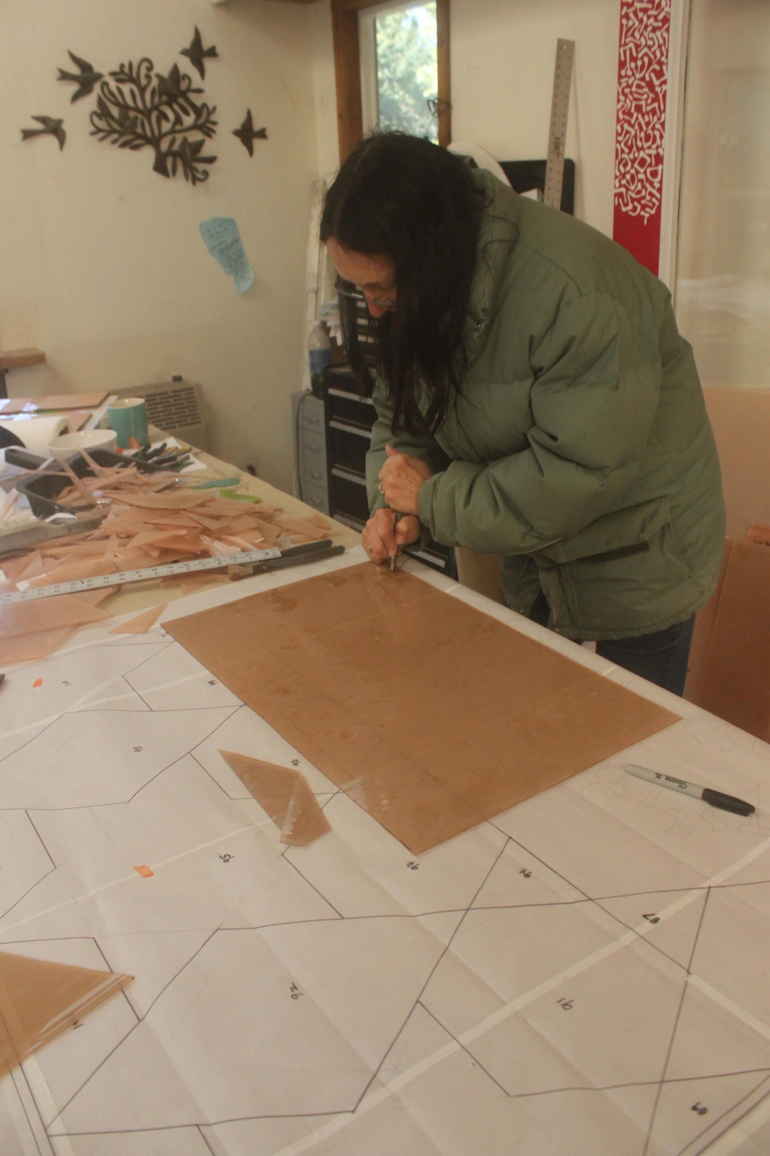 Michelle, at the cutting table, scores another piece of the background glass.