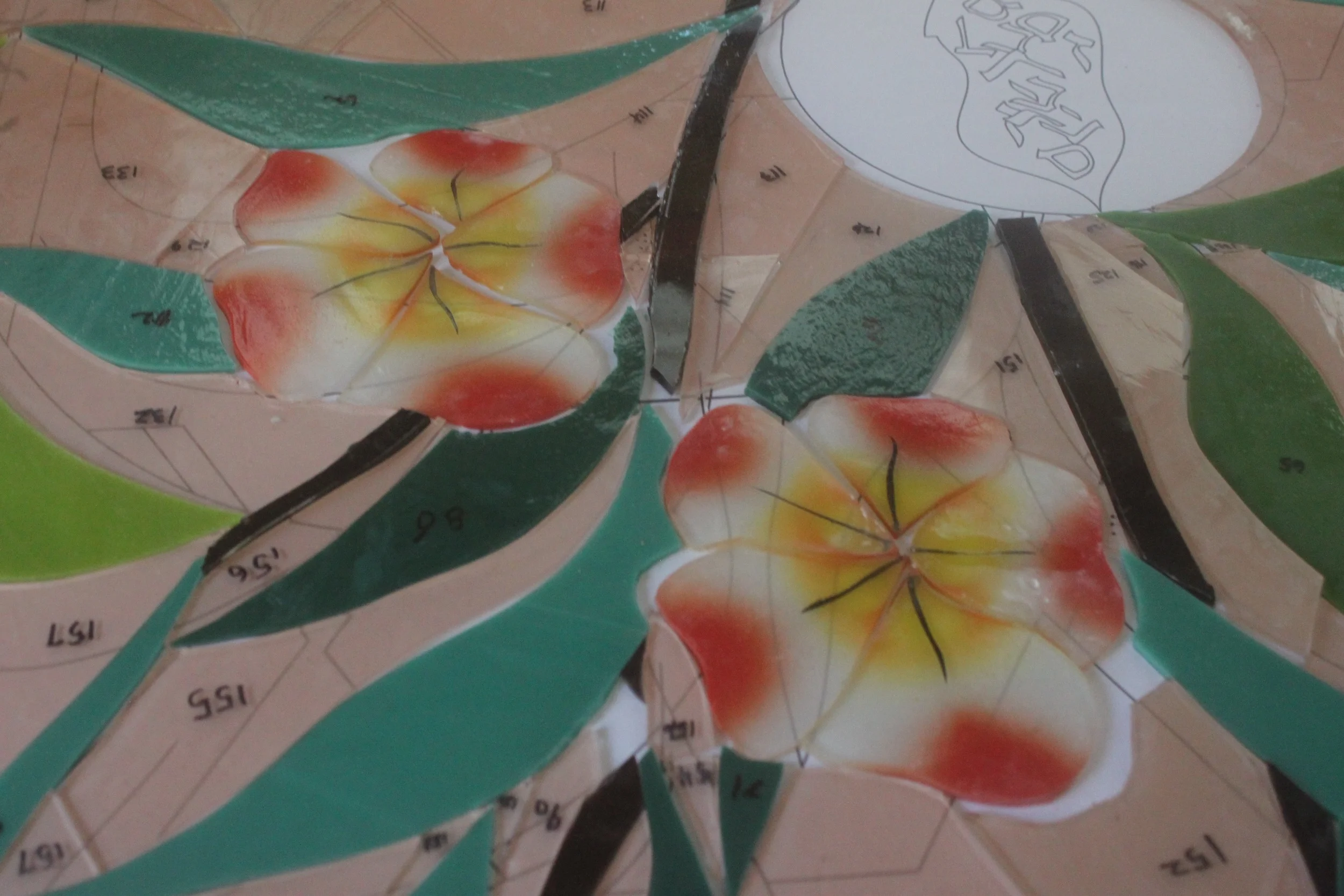 Painted flower petals having been fired and returned from the kiln are laid out on the pattern awaiting assembly.