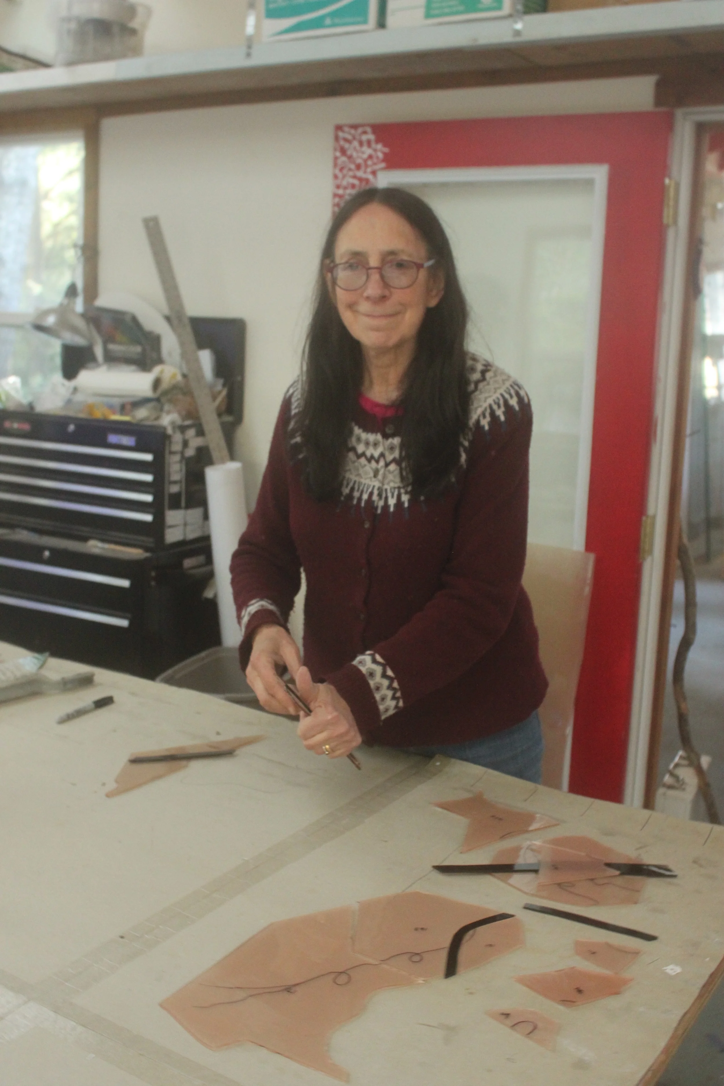 Michelle prepares pieces for the painting and firing on of the tendrils on the grapevine window.