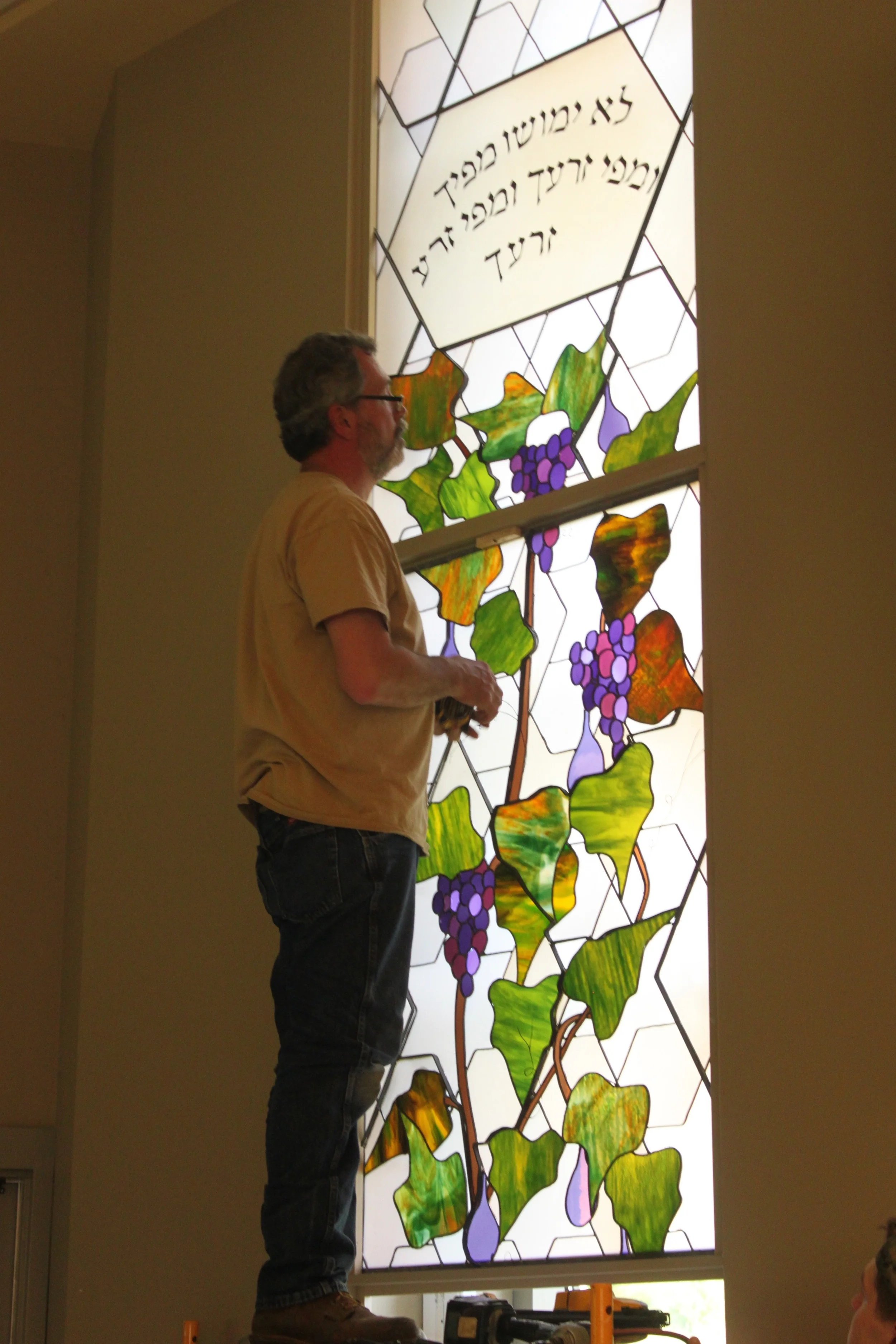David Rosenburger inspects the install of the second panel from the top on the left side of the sanctuary, at Temple Isaiah.