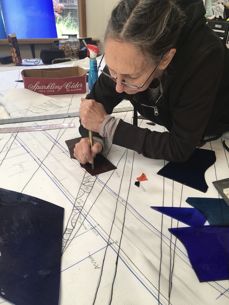 Michelle scores a piece of glass, working right over the pattern.