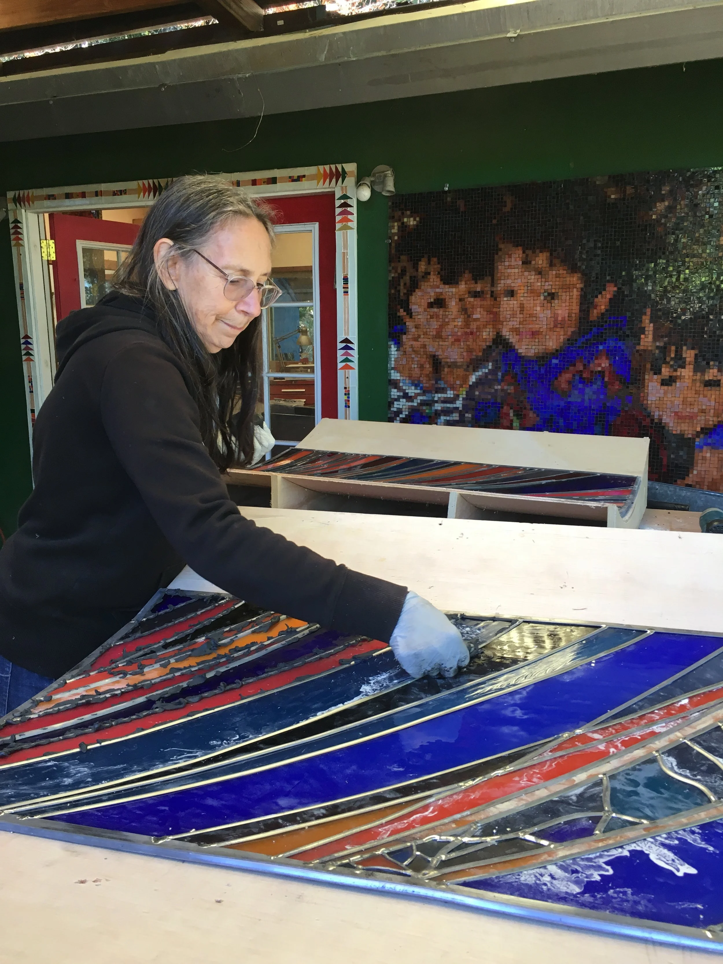  Michelle applies putty to the back surface of a panel. 