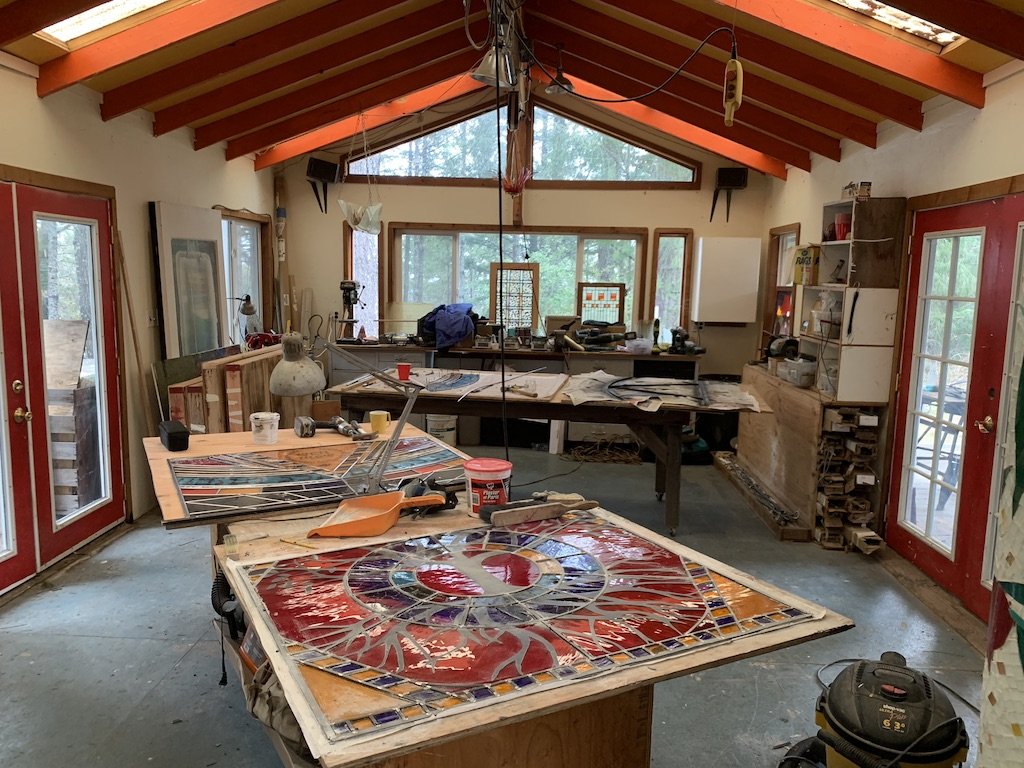 Studio crowded with panels being assembled, soldered and glazed