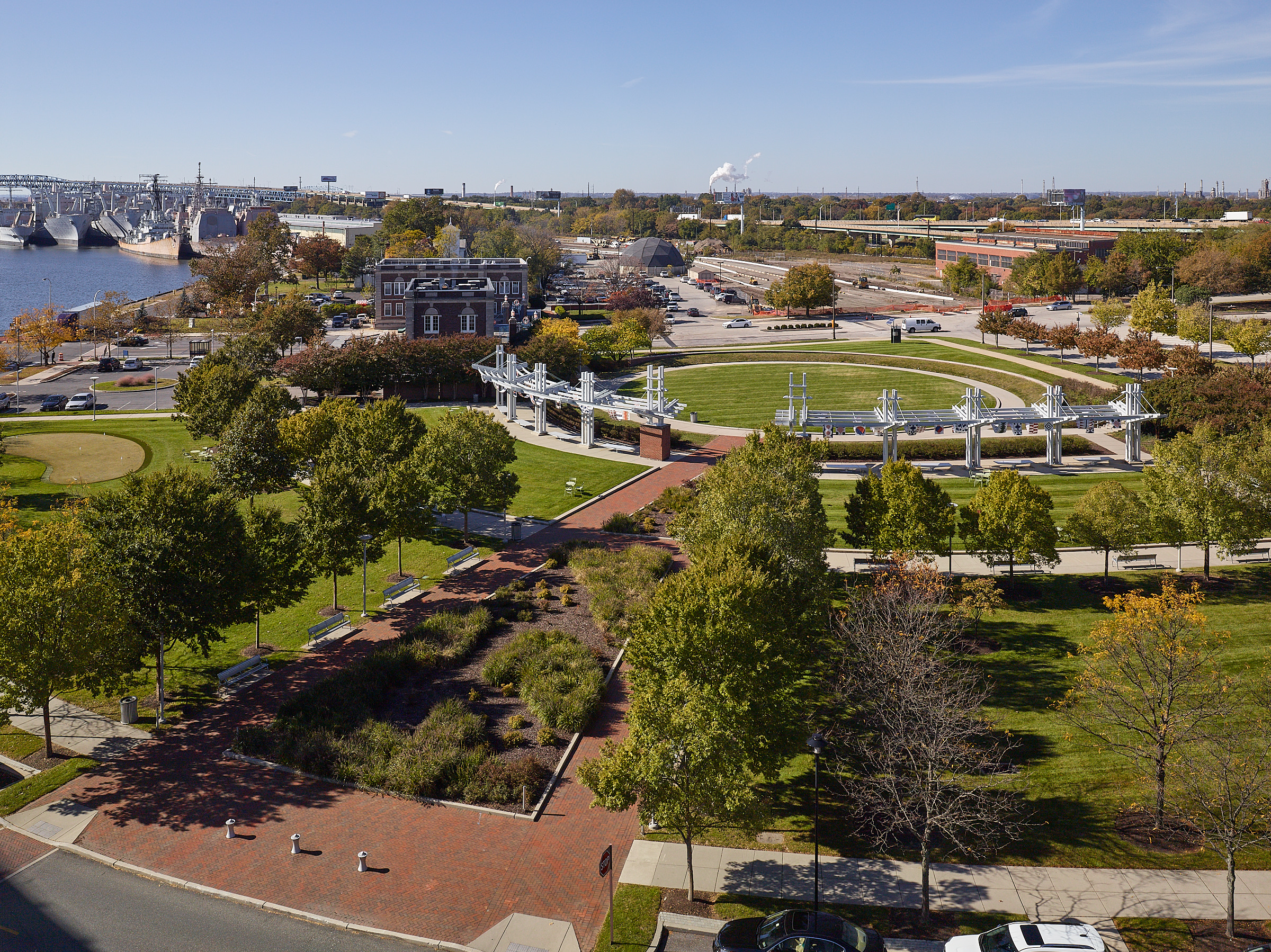 Crescent Park at the Navy Yard, Philadelphia, PA Crescent Park, at the terminus of Broad Street, fulfills the vision of a master plan initiated by the Philadelphia Industrial Development Corporation to create a memorable entrance to the 21st century reincarnation of the decommissioned Navy Yard. As the initial piece of public infrastructure, the 3.46-acre park set the stage for level of finishes and vocabulary of materials. Formal lawn panels, stands of trees, perennial beds and seating areas support passive recreation and repose for office tenants, with a putting green for those who want to practice their swing. A massive steel pergola evocative of naval architecture curves in an arc around the site for 200 feet, merging the past and present in one landscape.
