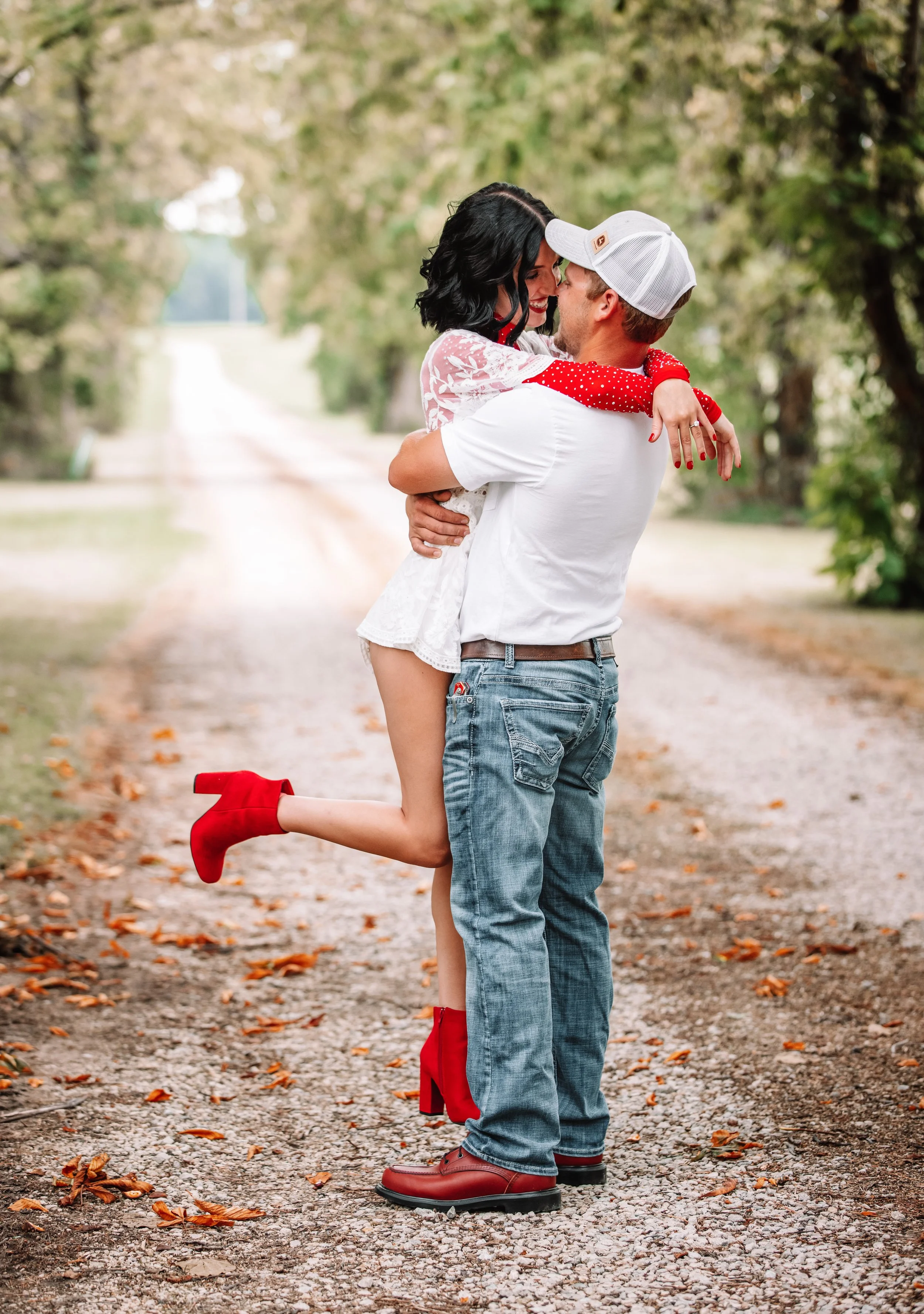 Engagement photo session of couple in tree lined lane  boyfriend picking up girlfriend