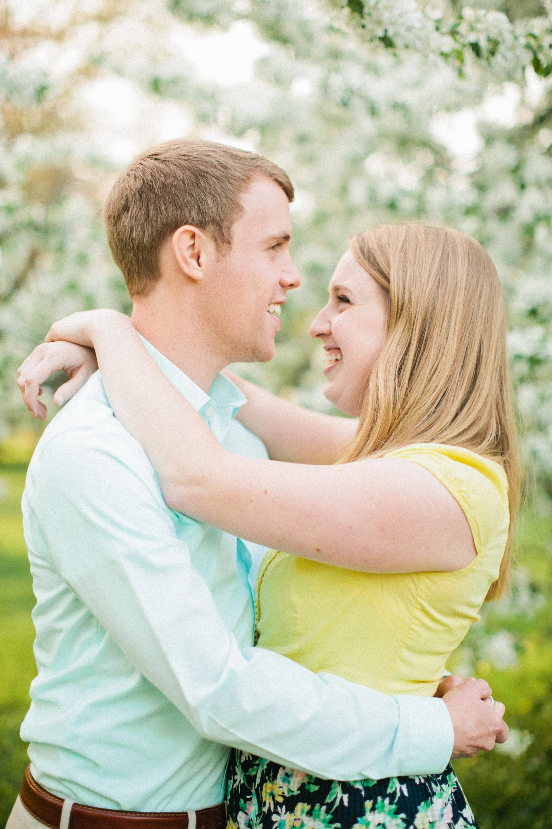 couple hugging in front of white cherry flowers in des moines park