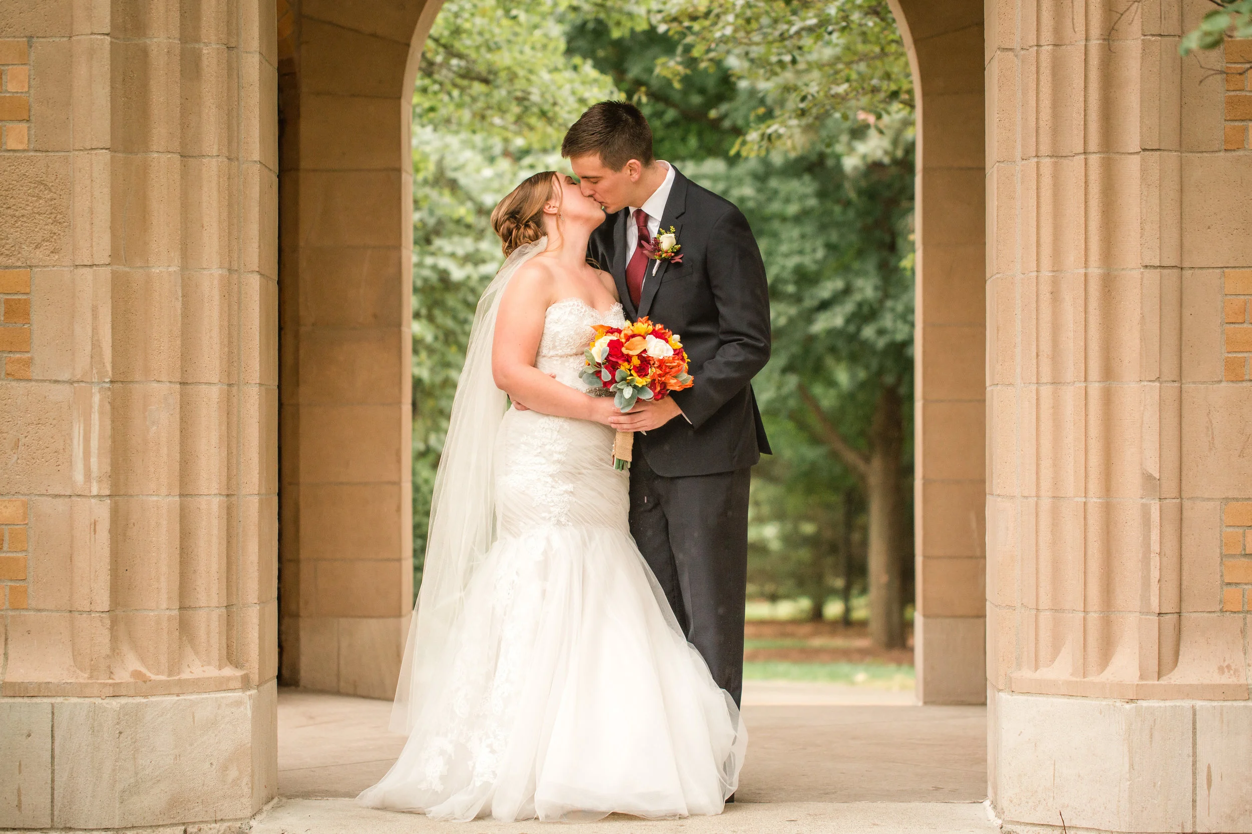 bride and groom kissing under iowa state campanile