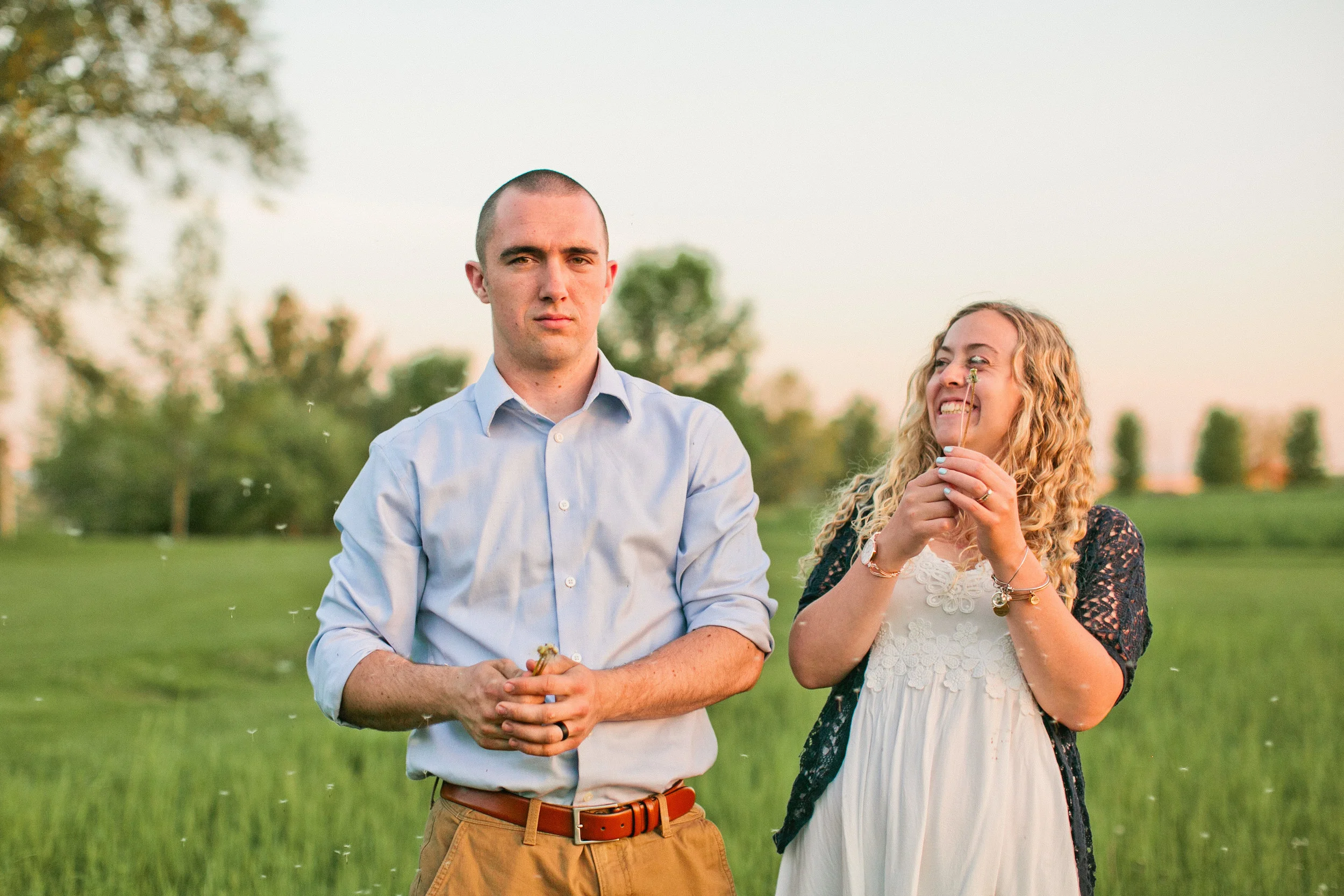 couple blowing dandelions in field engagement photos saylorville iowa