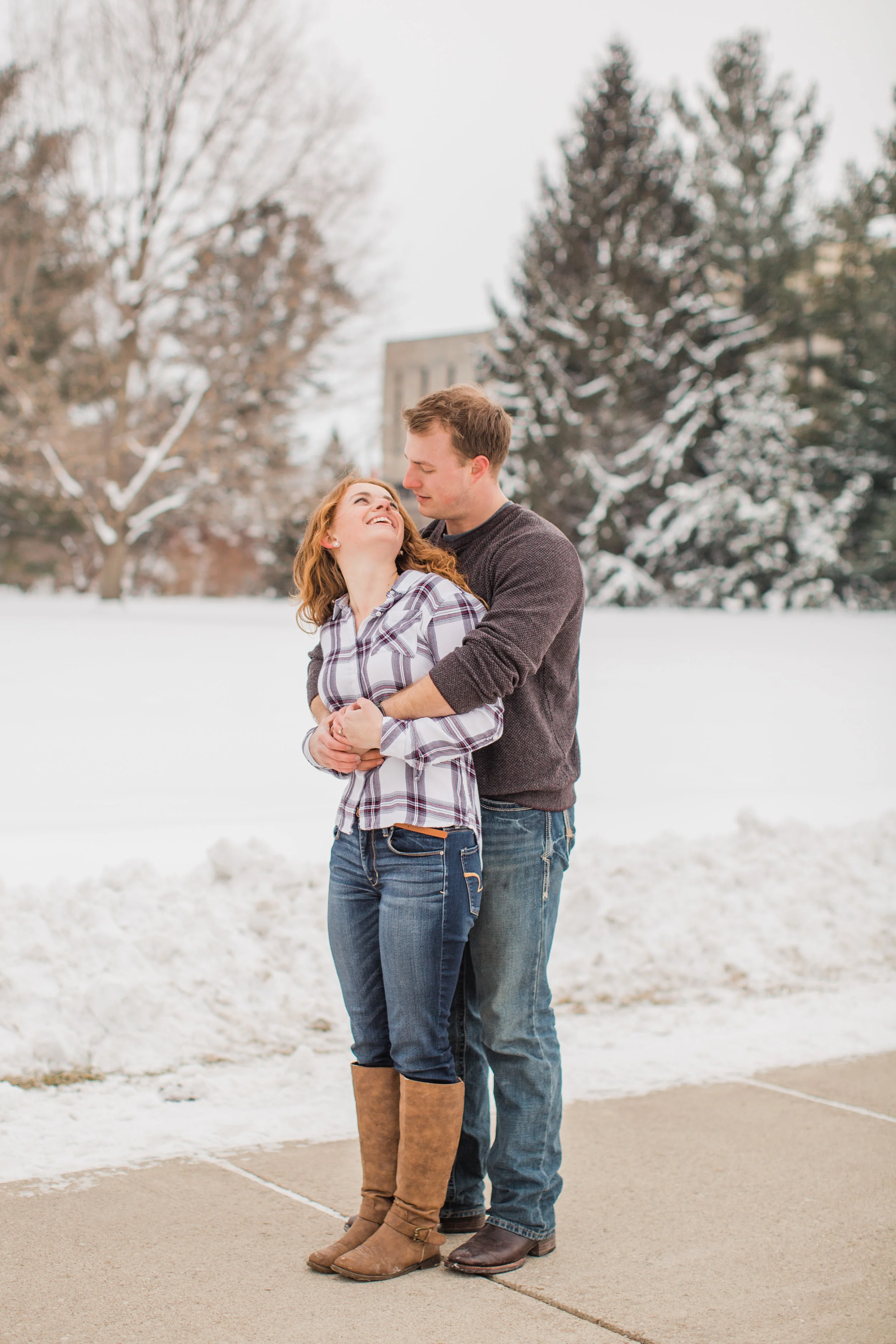 cute couple hugging and laughing in the snow Des Moines Iowa winter engagement pictures