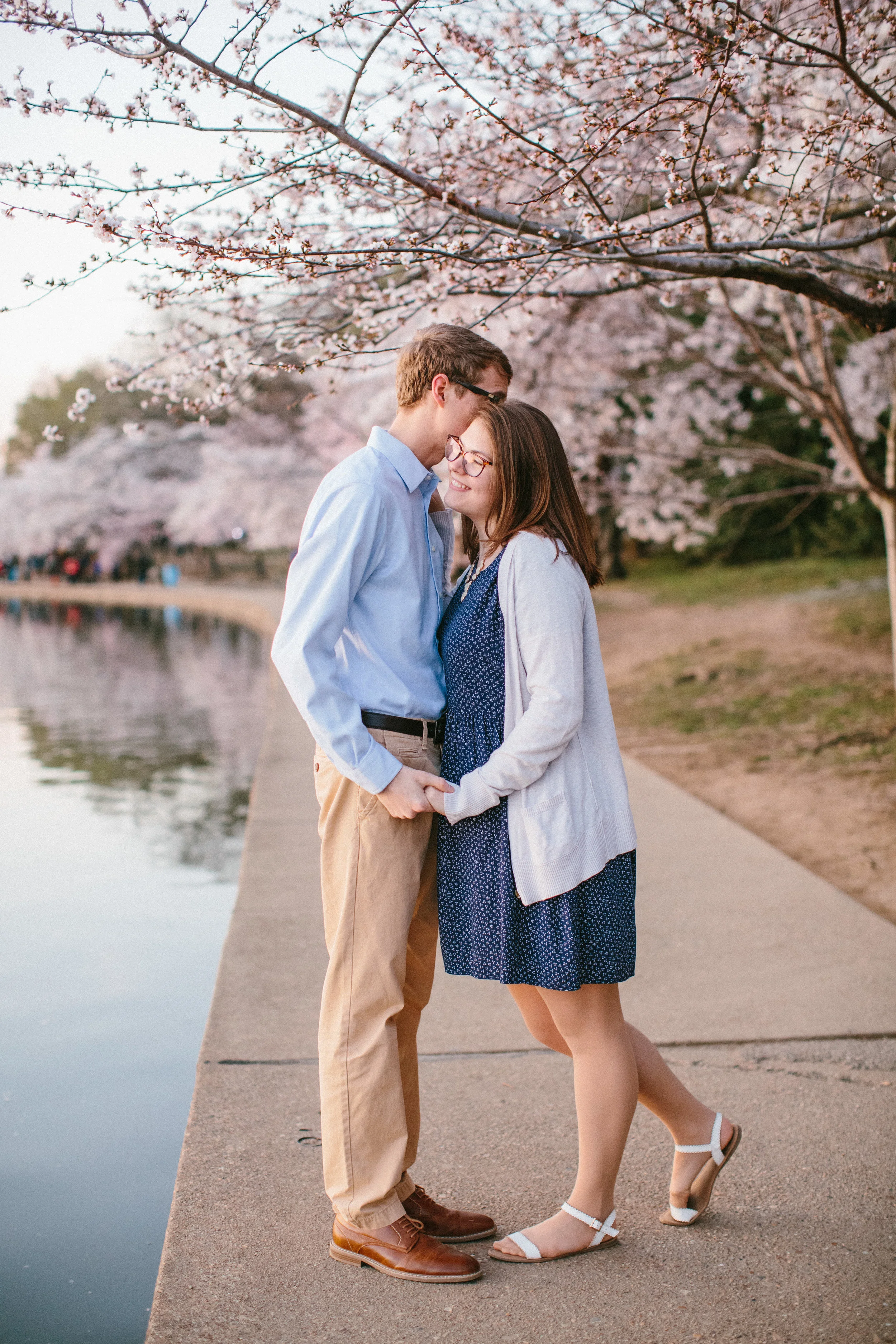 guy and girl hugging under blooming cherry tree Washington DC tidal blossoms