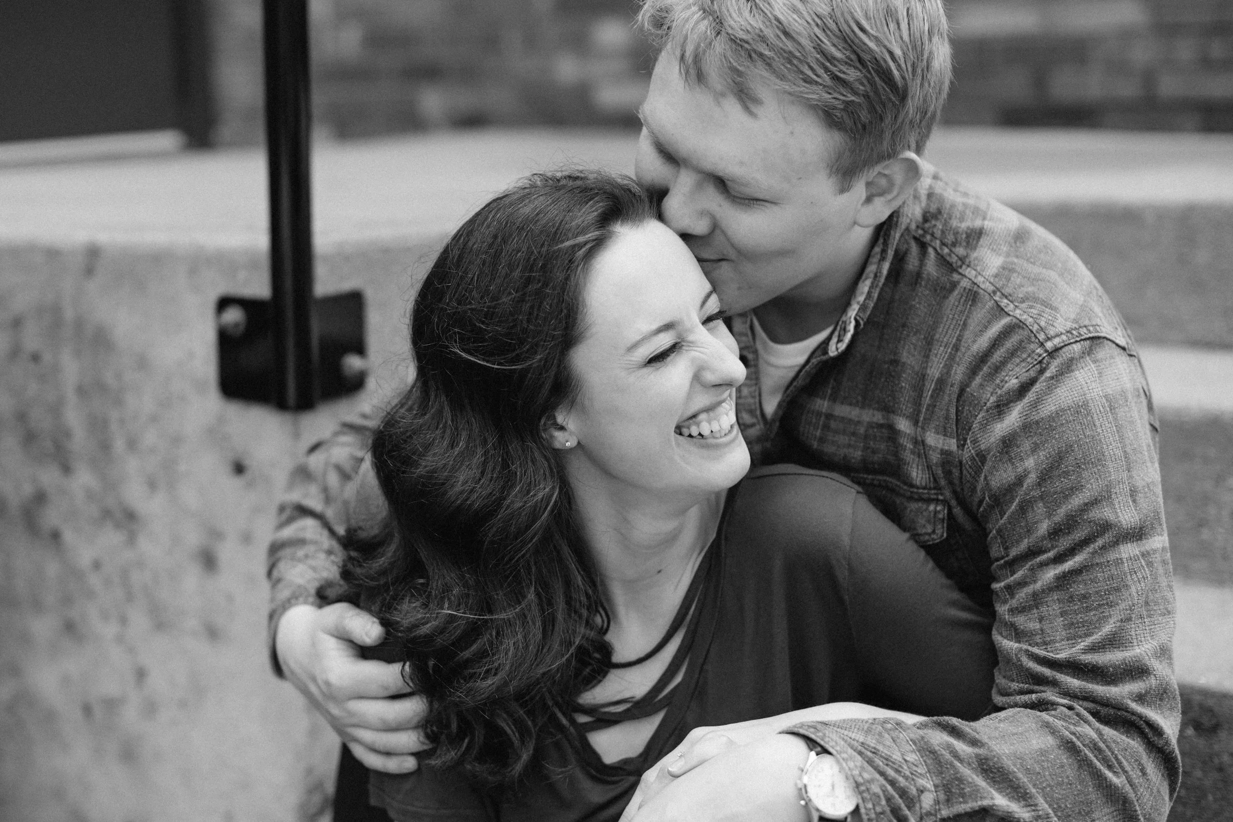 couple kissing and snuggling sitting on steps downtown des moines engagement pictures