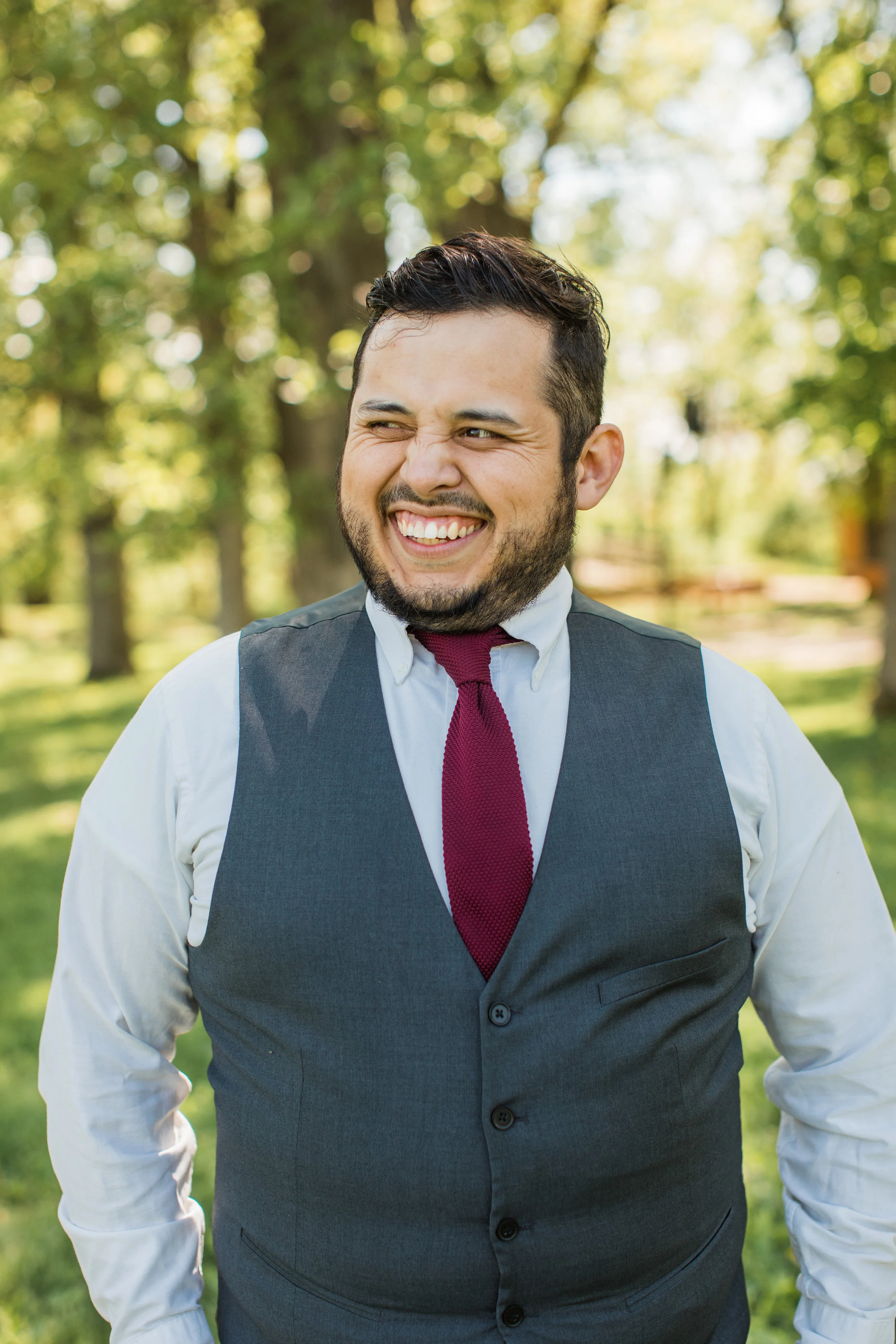 groom laughing and wearing grey vest for wedding outdoors Iowa des moines photographers