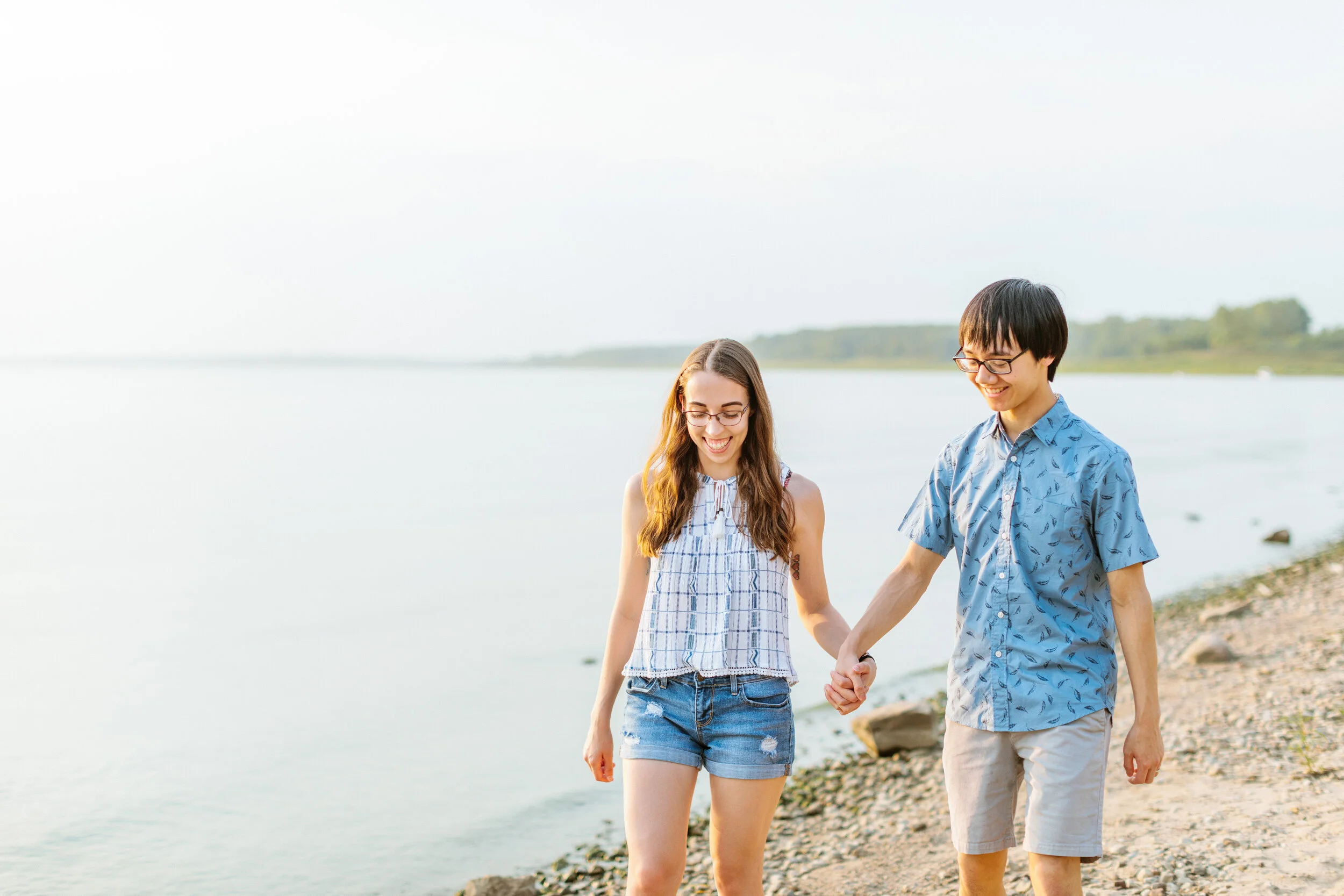 couple walking along beach holding hands engagement photos des moines iowa saylorville lake