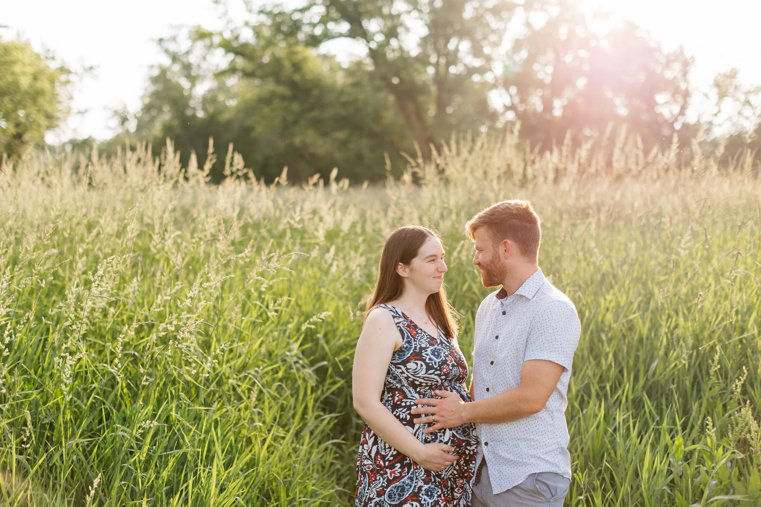 couple taking maternity photos in tall grass des moines