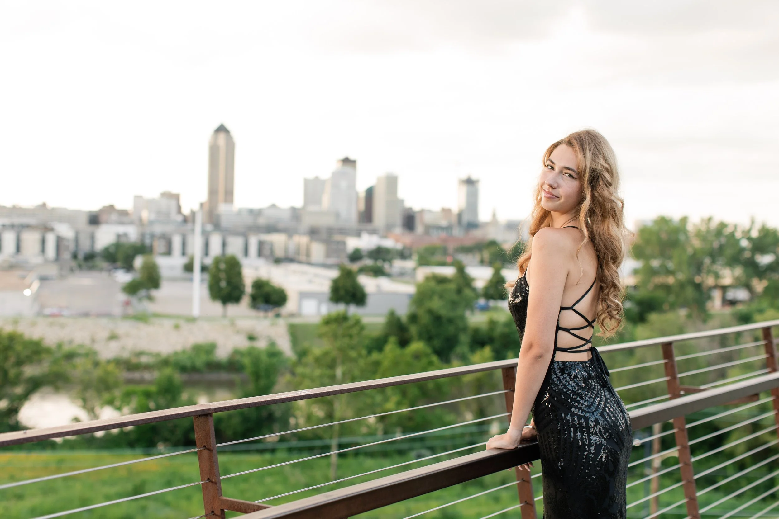des moines skyline behind senior girl on bridge