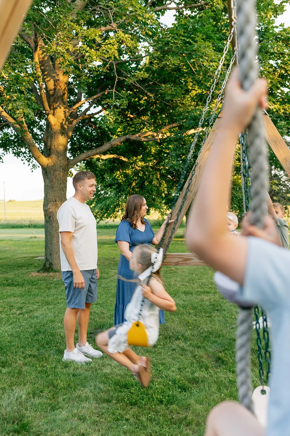 parents watching kids on swingset family photographer cedar falls iowa