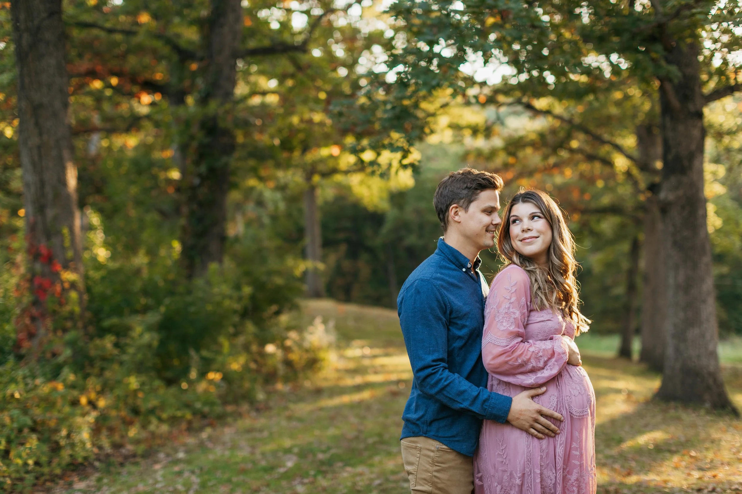 couple takes fall maternity photos in des moines park wearing pink blue clothing