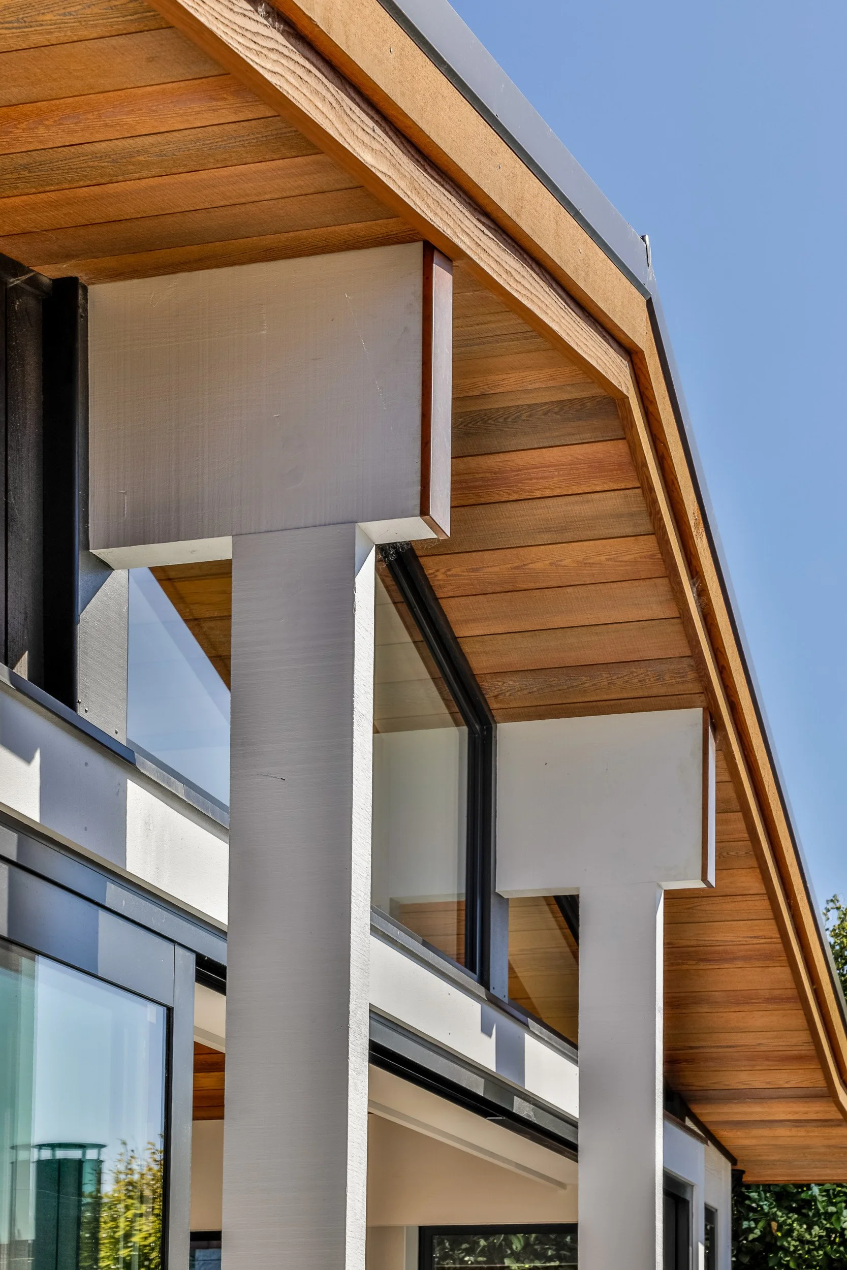 Close-up of a modern house exterior showing a combination of wood, glass, and concrete with a sloped wooden roof.