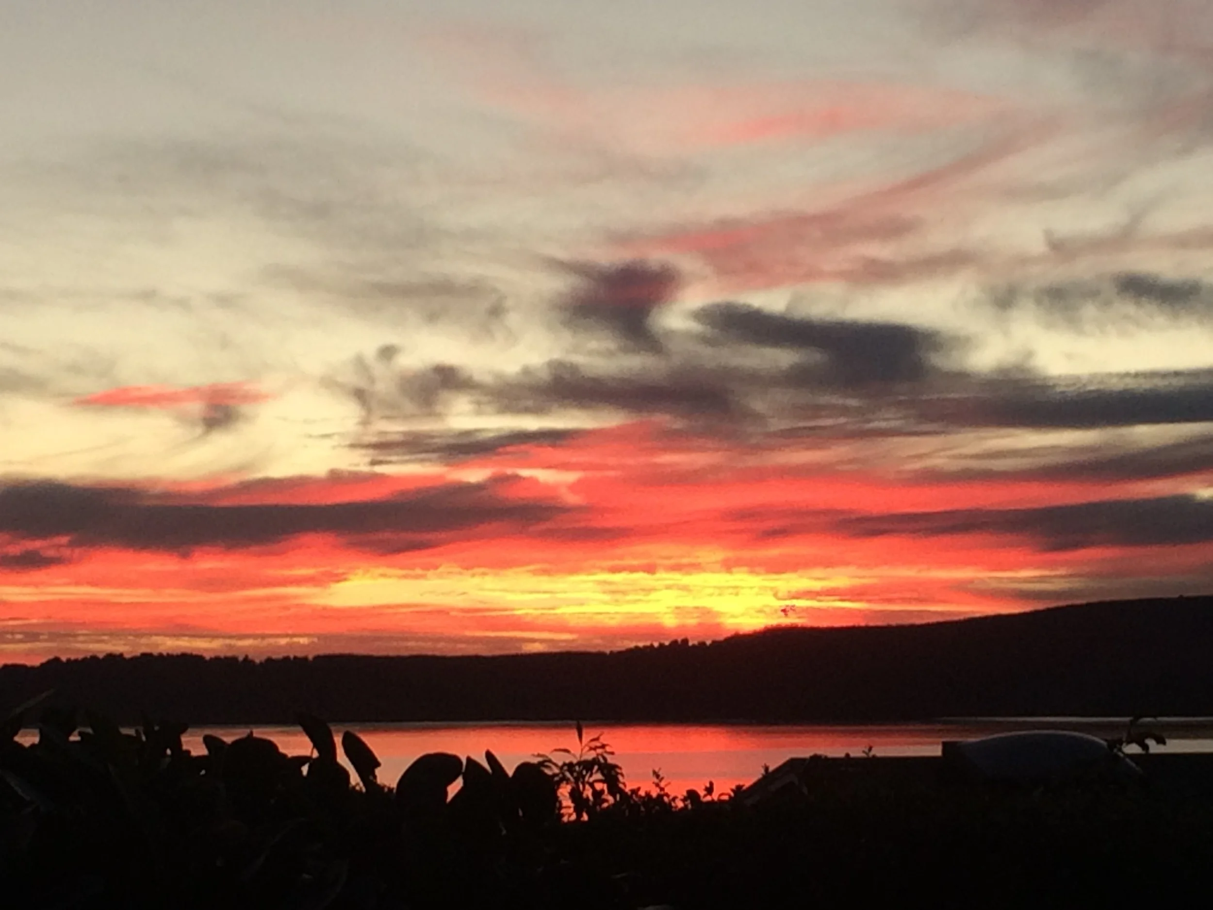 Sunset over a body of water with colorful clouds in the sky.