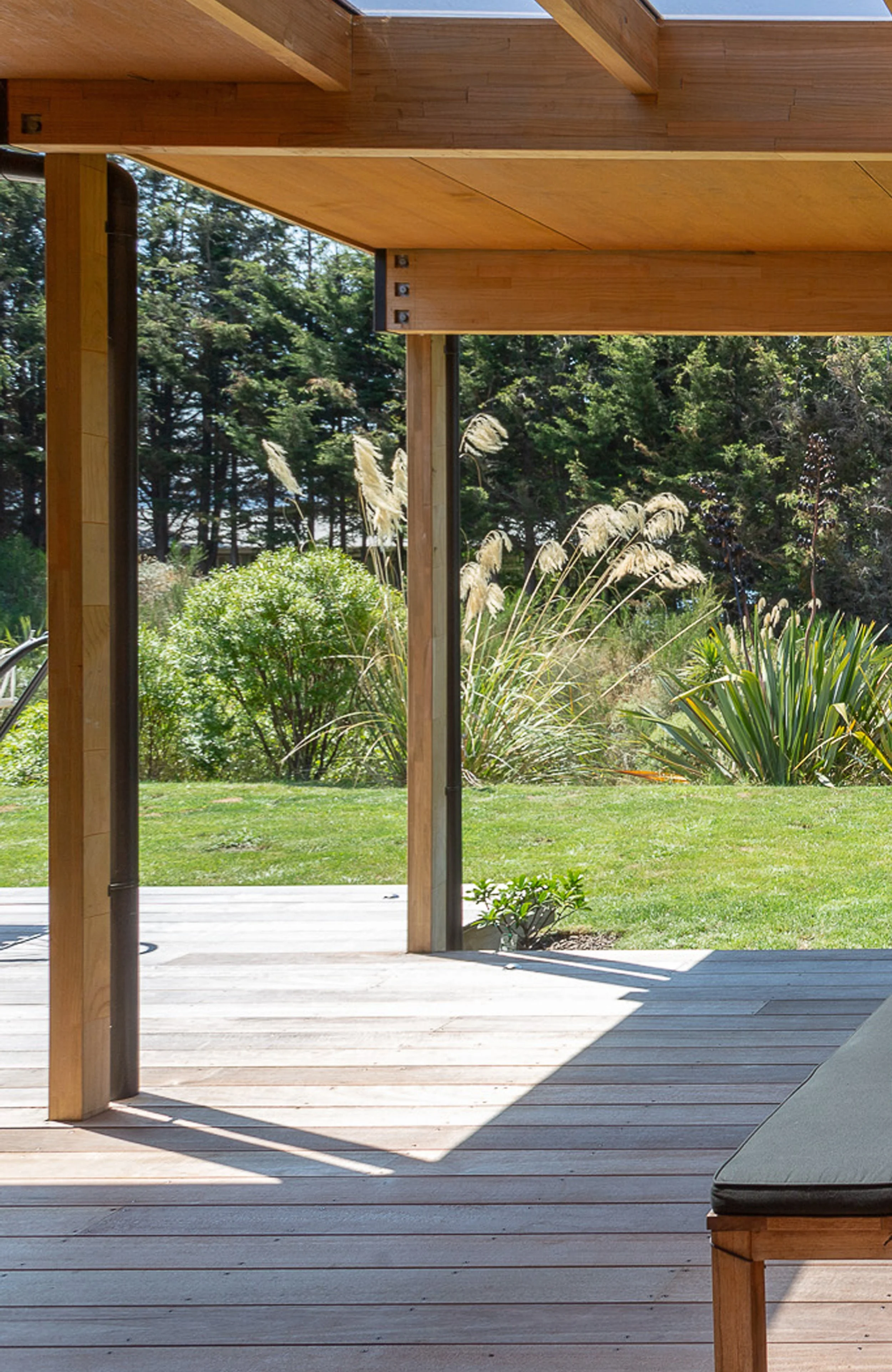 Wooden deck with a garden view, grass, bushes, tall grasses, and trees in the background.