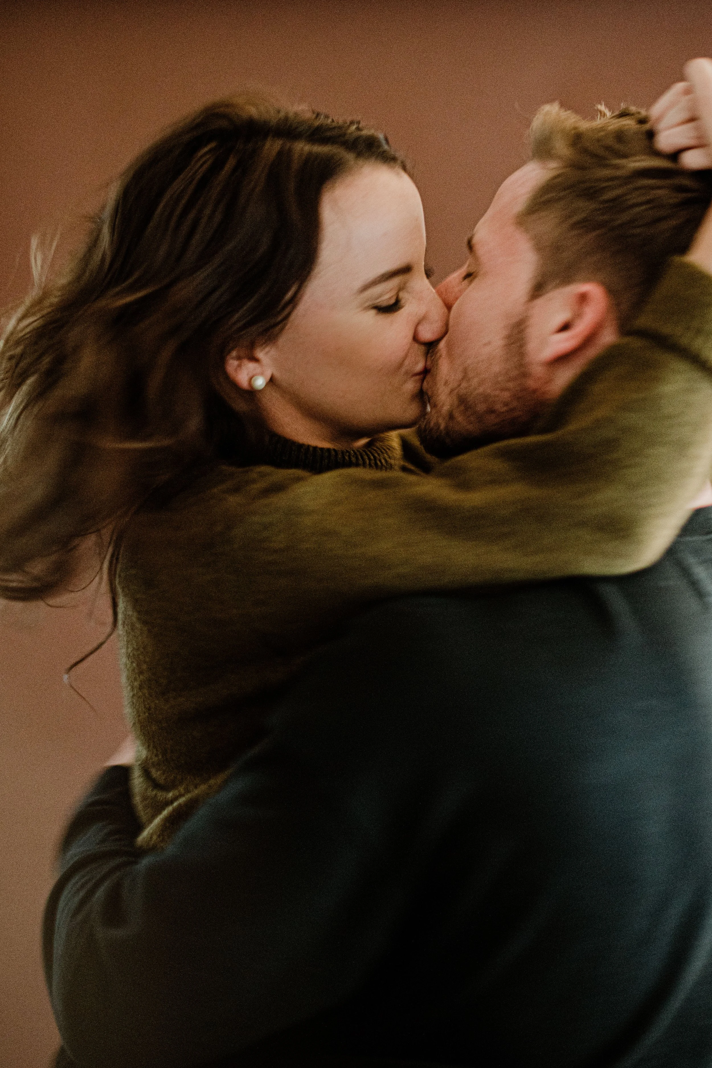 A woman and man sharing a kiss, with the woman holding the man's hair back.