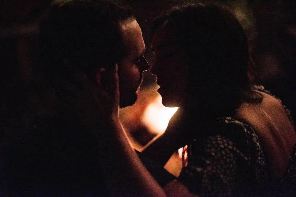 A silhouette of a man and woman facing each other in a romantic setting, with warm lighting highlighting their faces.
