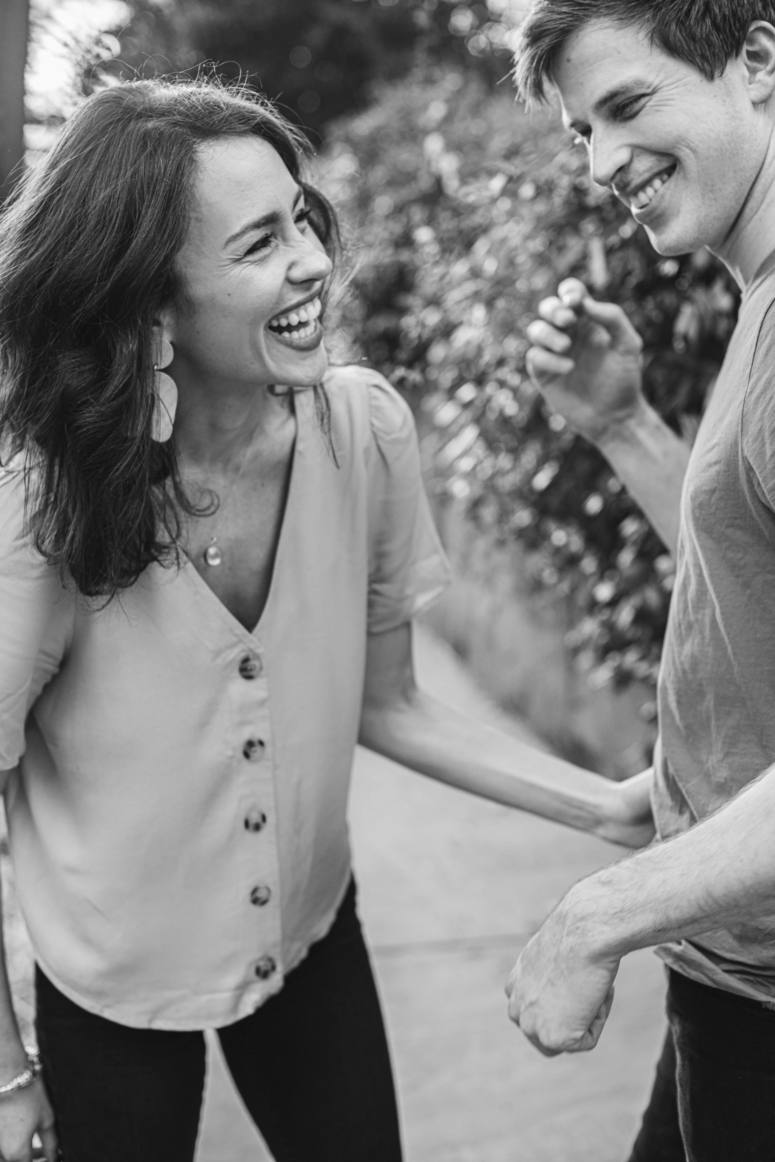 A smiling woman and man holding hands, outdoors, joyful interaction.