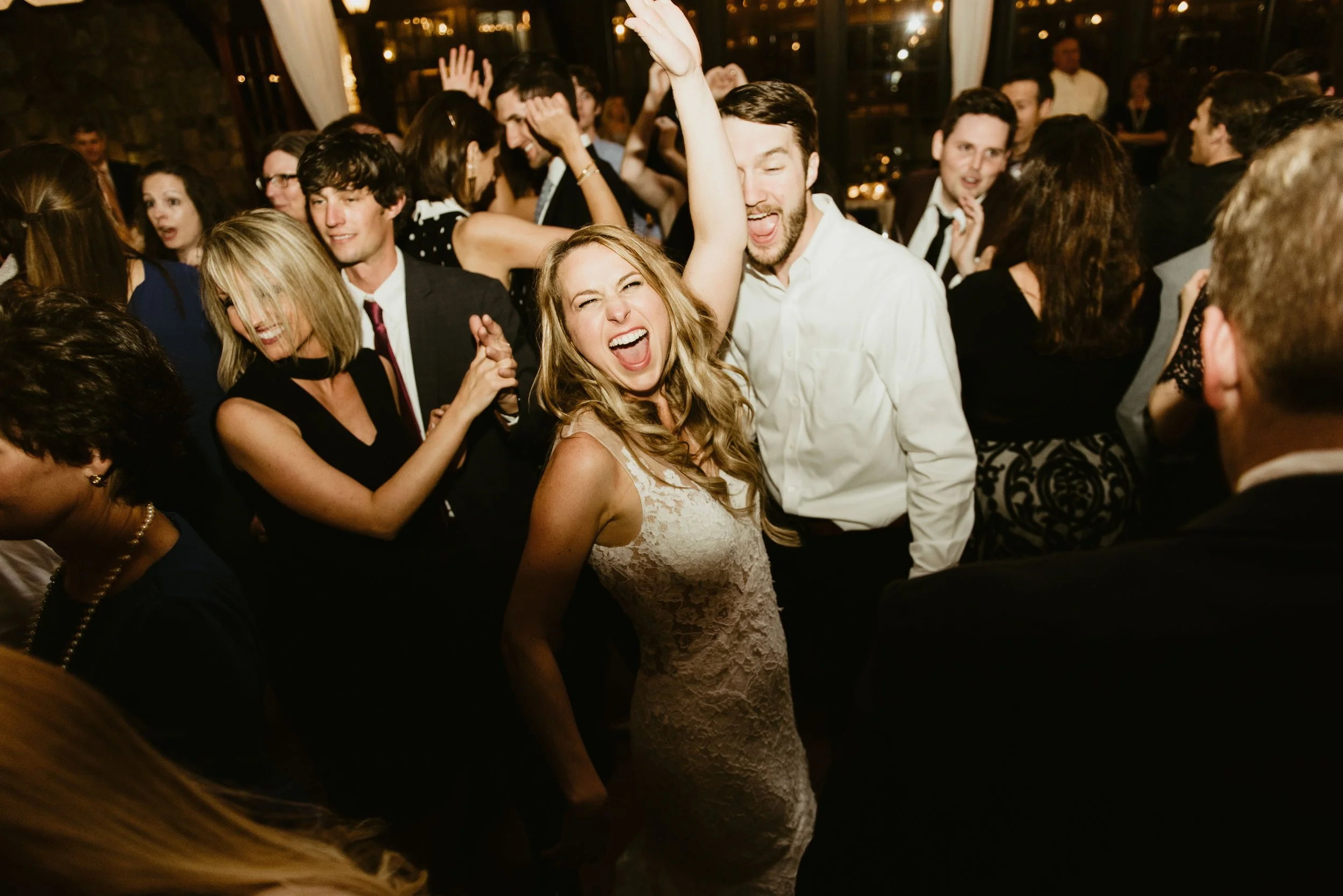 People dancing and celebrating at a lively party or wedding reception, smiling and enjoying themselves.