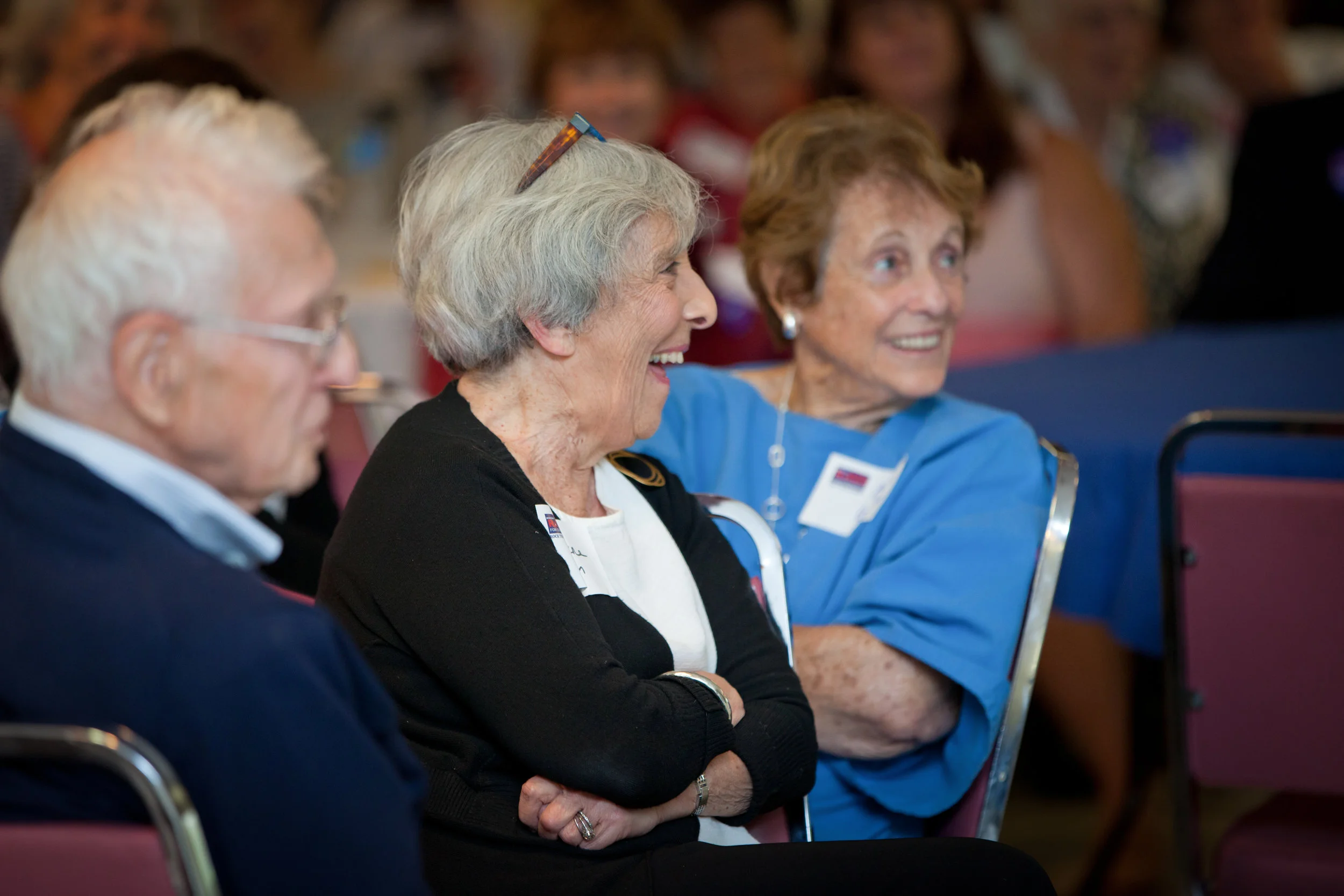 Three people seated in a row, smiling and laughing during a congressional campaign event.