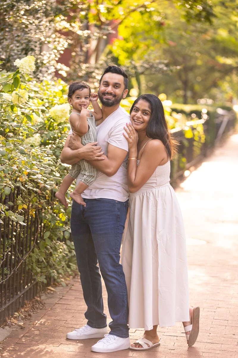 Outdoor family portrait of couple and baby smiling at the camera in the Capitol Hill neighborhood of Washington, D.C.