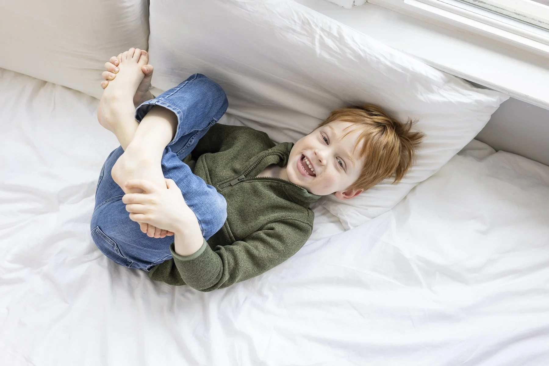 Candid lifestyle portrait of young boy on a bed during a family portrait session.