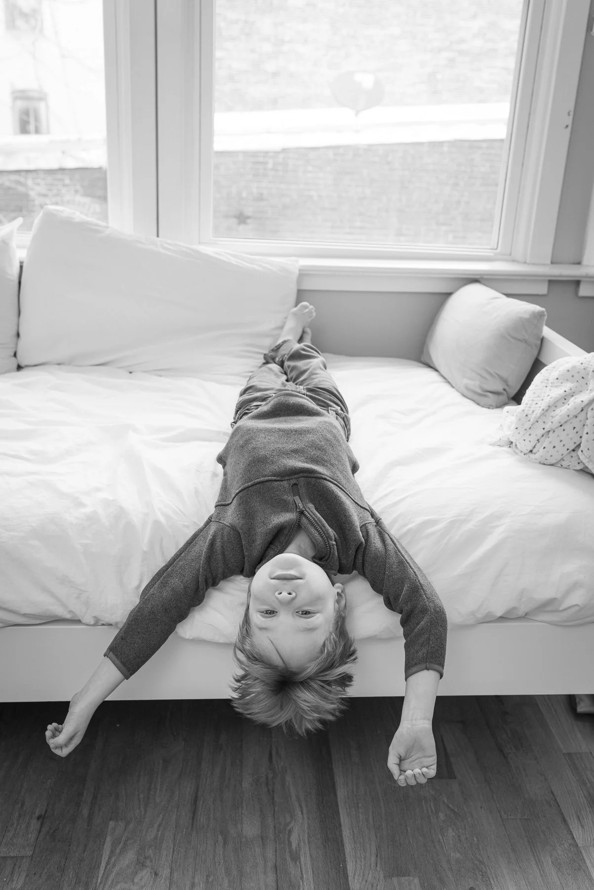 Candid lifestyle portrait of young boy on a bed during a family portrait session.