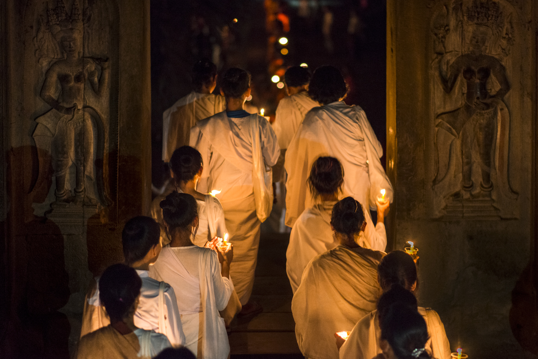 Nuns entering to Angkor Wat between two devata carvings. In buddhist and hindu mythology, devatas and apsaras are heavenly beings sent to earth by the gods to embody the feminine forces of the universe.