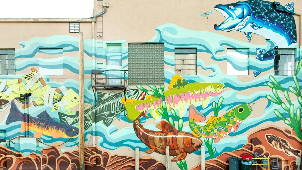 Gill Street , the collaborative fish mural can be seen from the parking lot behind Coal Creek Coffee and Alititude's Chophouse at First and Grand and First and Garfield, or from the historic Garfield Street Footbridge. It was dedicated on June 13, 2014. Artist Include: Colleen Friday, Jeff Hubbell, Travis Ivey, Evan Levi, Chelsea Lowry, Meghan Meier, Lindsay Olson, Dan Toro, Adrienne Vetter.