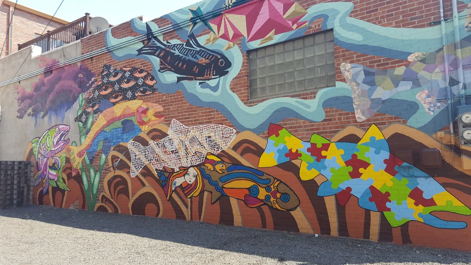 A school of finish painted in different styles on a brick wall