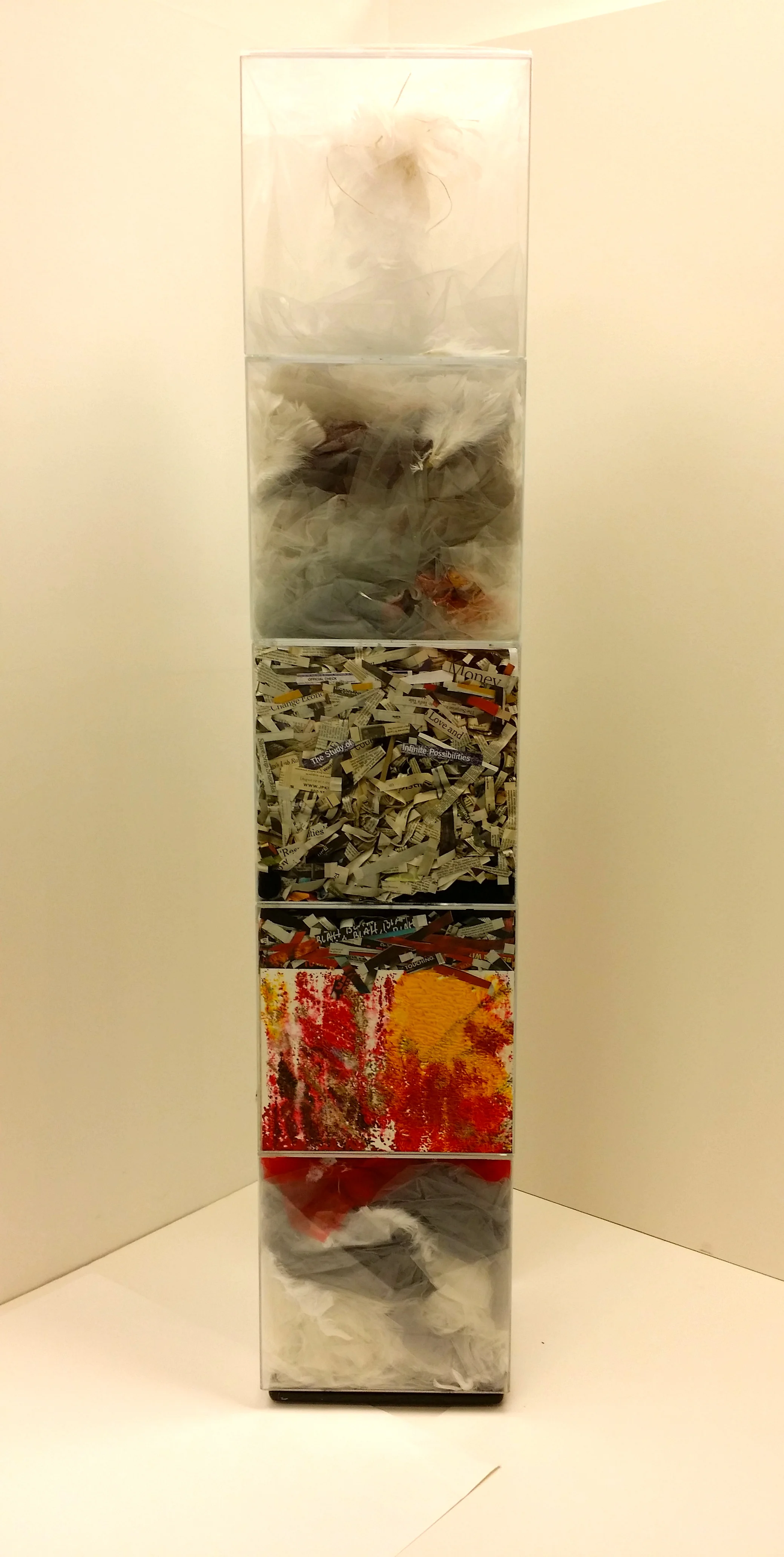An Hypothesis, 2015 12 x 12 x 62 inches Five acrylic cubes containing dyed gray gauze, lightweight tulle, feathers, newspaper clippings, textured acrylic drawings, and dripped paint, arranged in the boxes so as to fill and modify their space. Each cube defines a separate space, yet the content of each bleeds into the next, connecting them into the whole. While the contents can be seen as unrelated, they can also be perceived as one in essence. The stacked boxes suggest an orderly sequence, hinting at a logical cycle in which the materials are arranged.