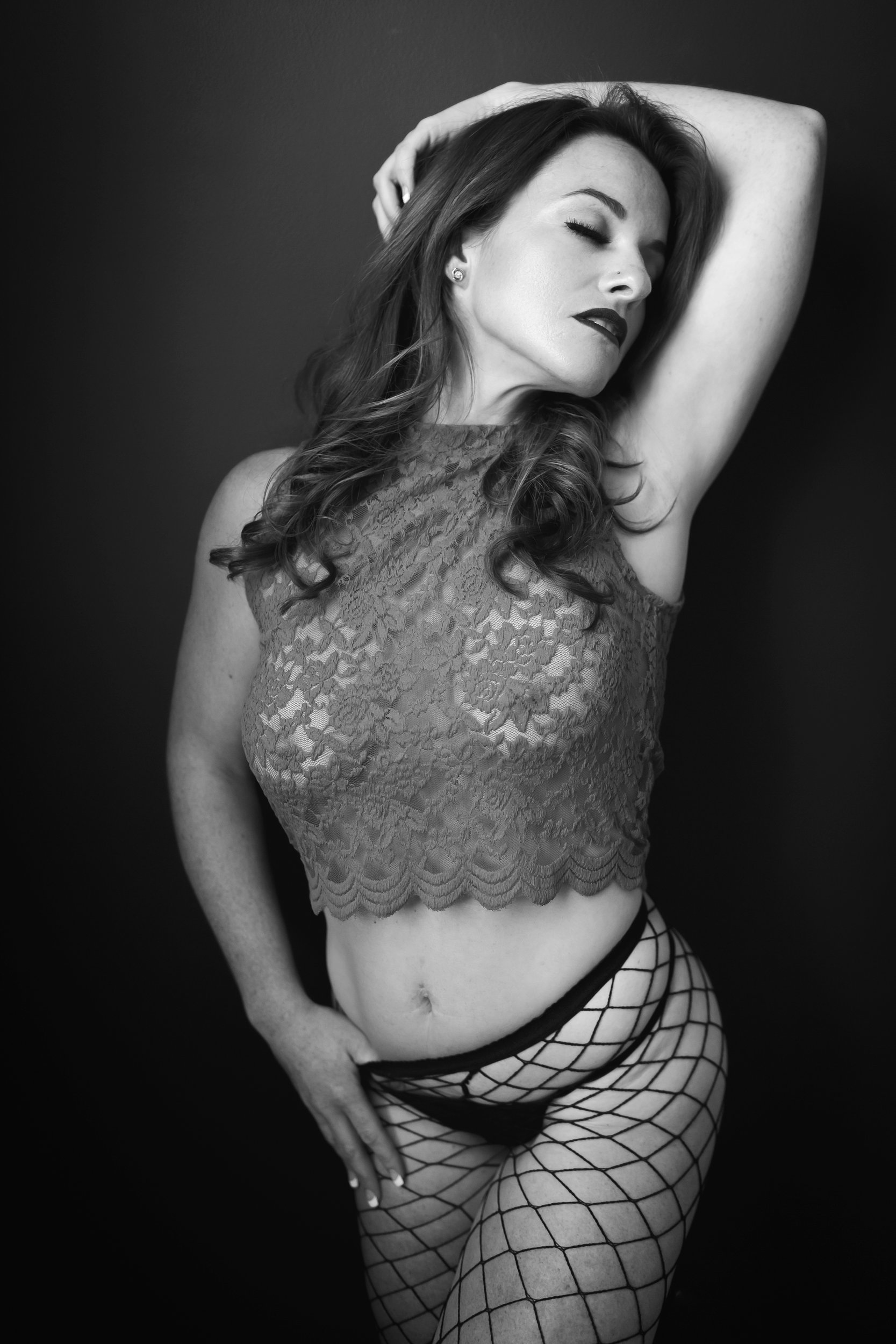 Black and white photo of woman in lace top and fishnet stockings